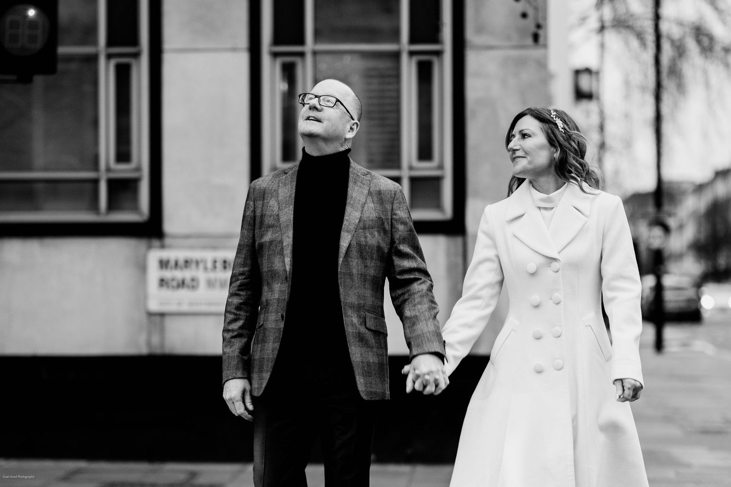 A black and white photo series showing a couple walking together while holding hands on a city street.