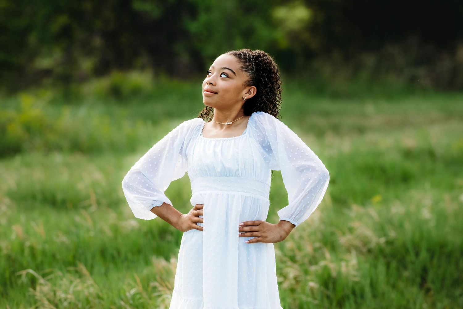 A person wearing a flowing white dress twirls joyfully in a sunny green meadow on a summer day.