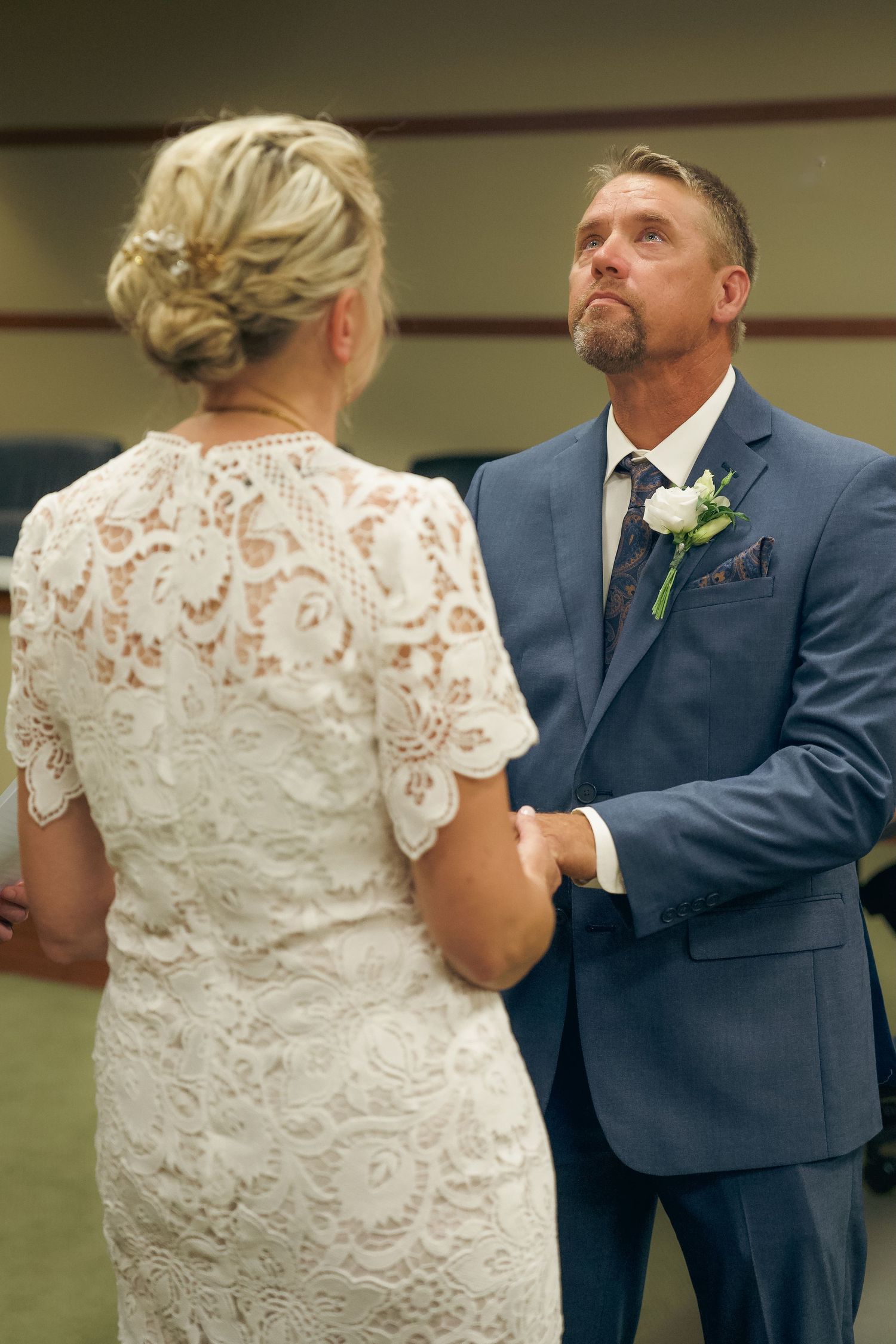A couple in wedding attire share a playful moment during their first dance in a reception hall.