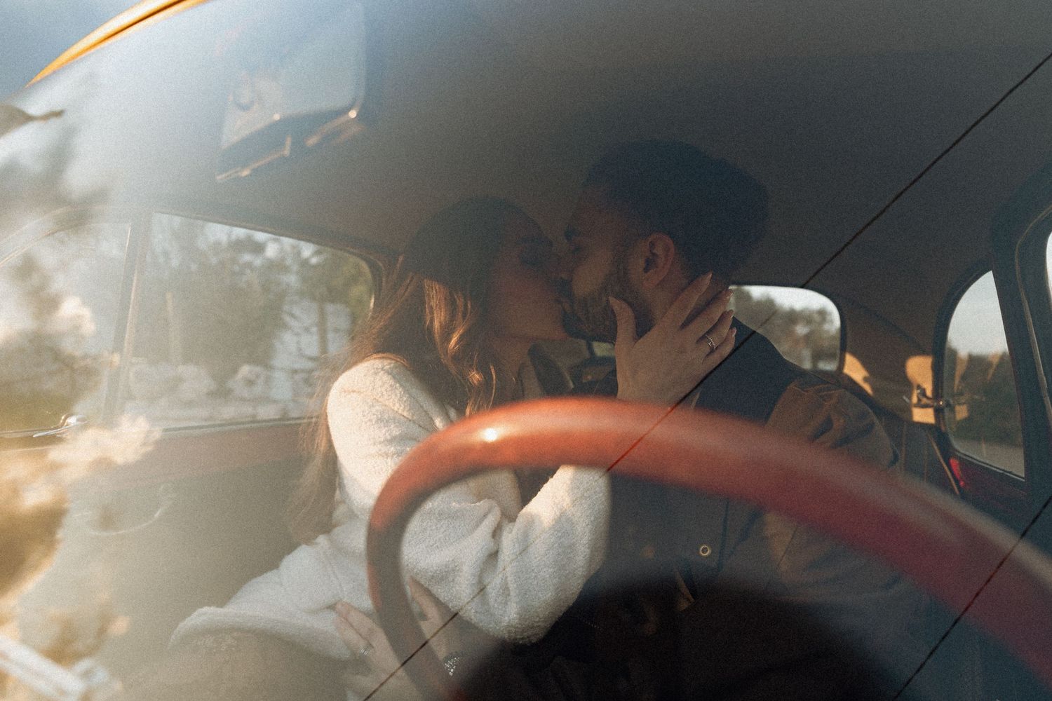 A person in a white dress sits in the back of a car during a wedding celebration.