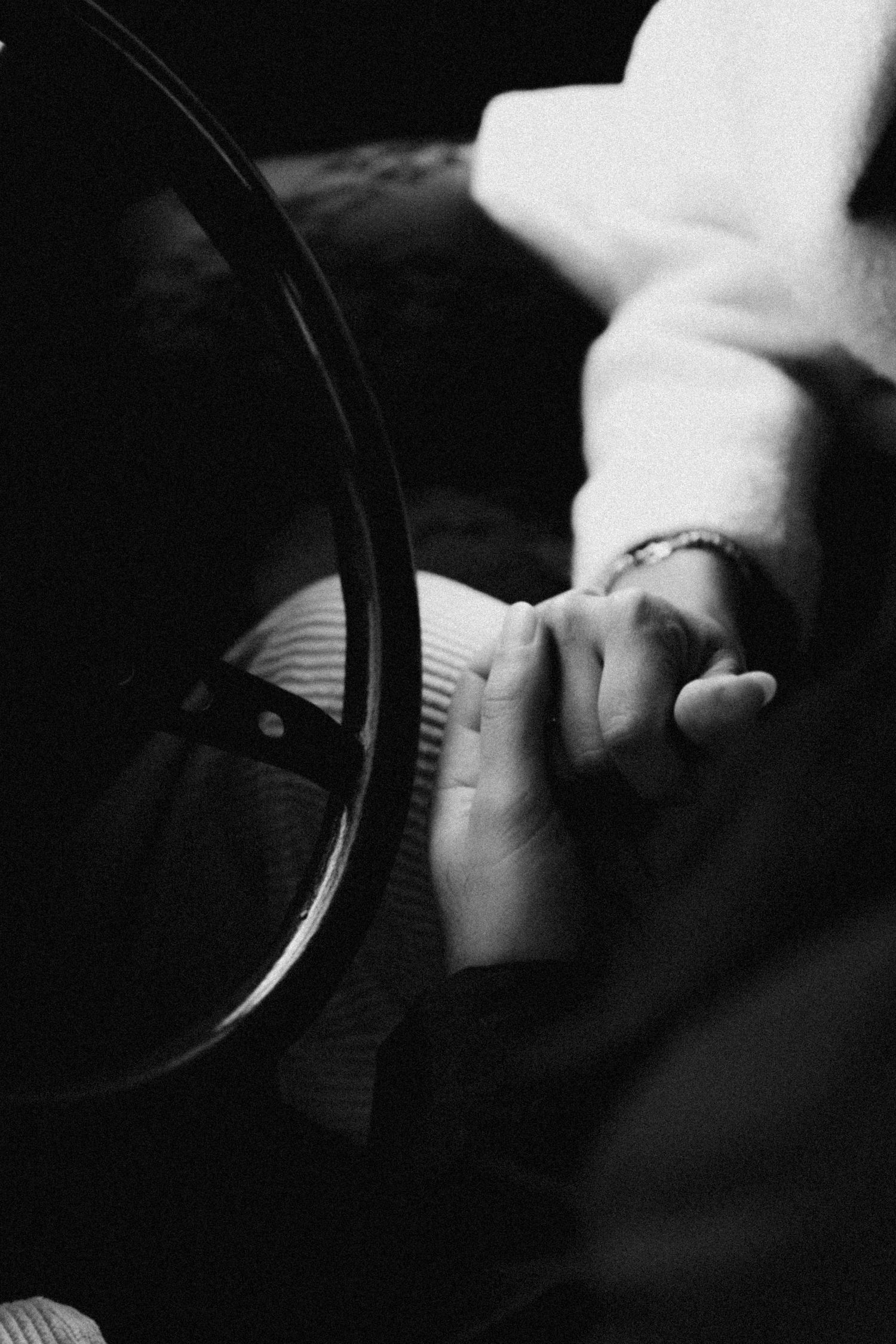 Close-up black and white photo of someone adjusting a camera lens in low light.