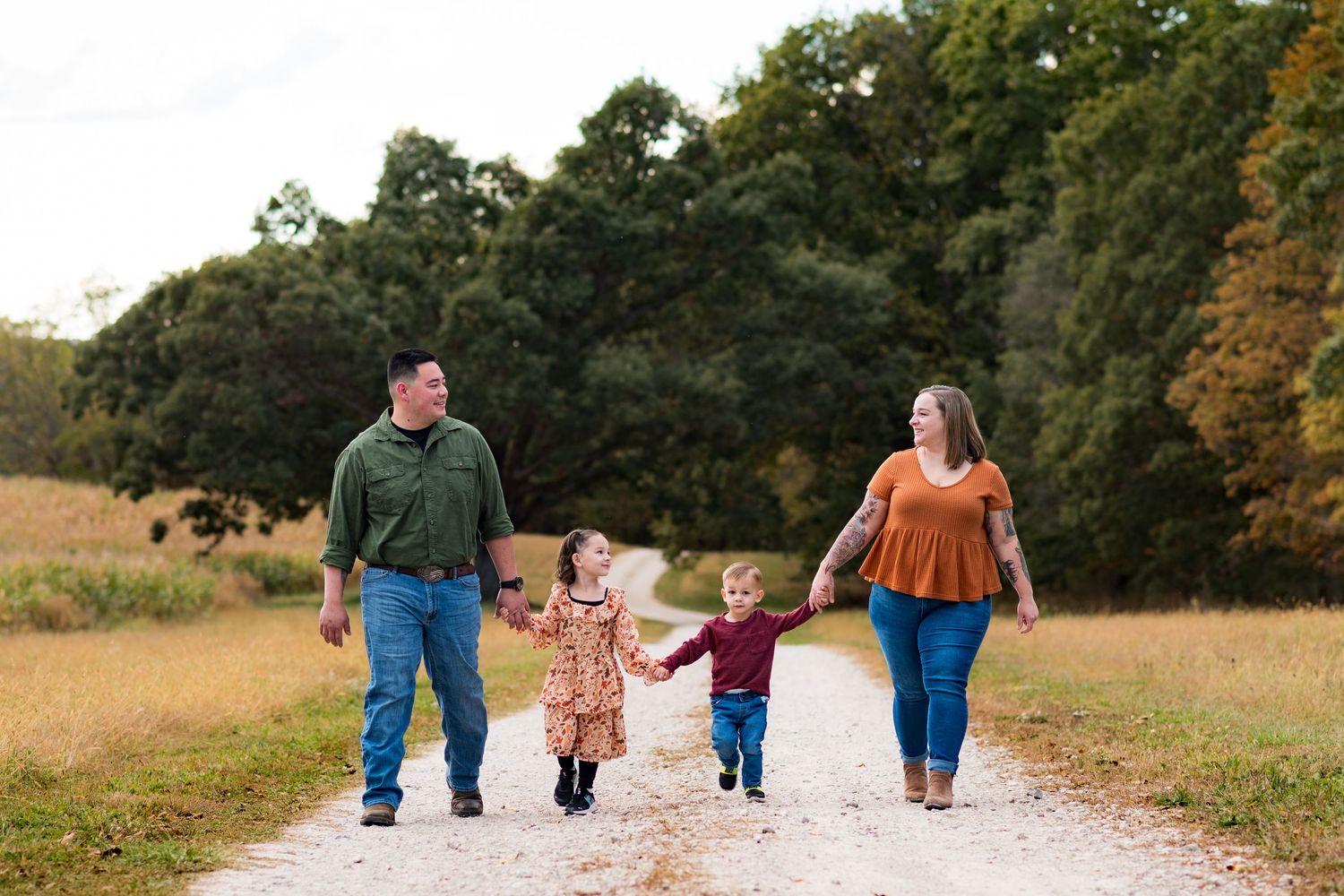 Family walking together on a path through an autumn field during golden hour.