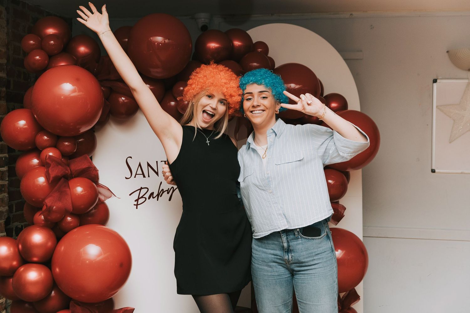 Two friends celebrating with vibrant red balloon decorations and party atmosphere.