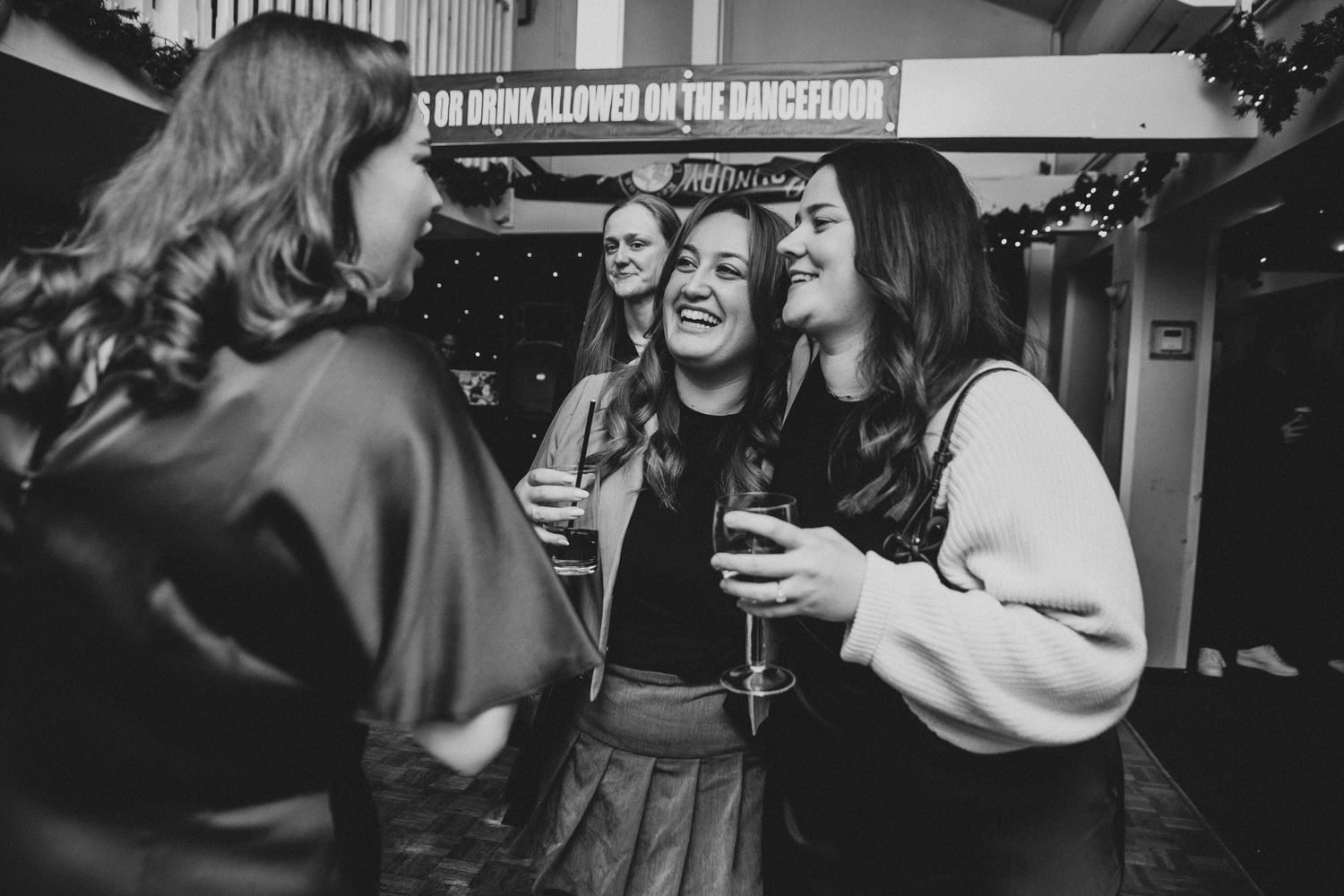 A lively dance party scene with people laughing and dancing in a dark room with ambient lighting.