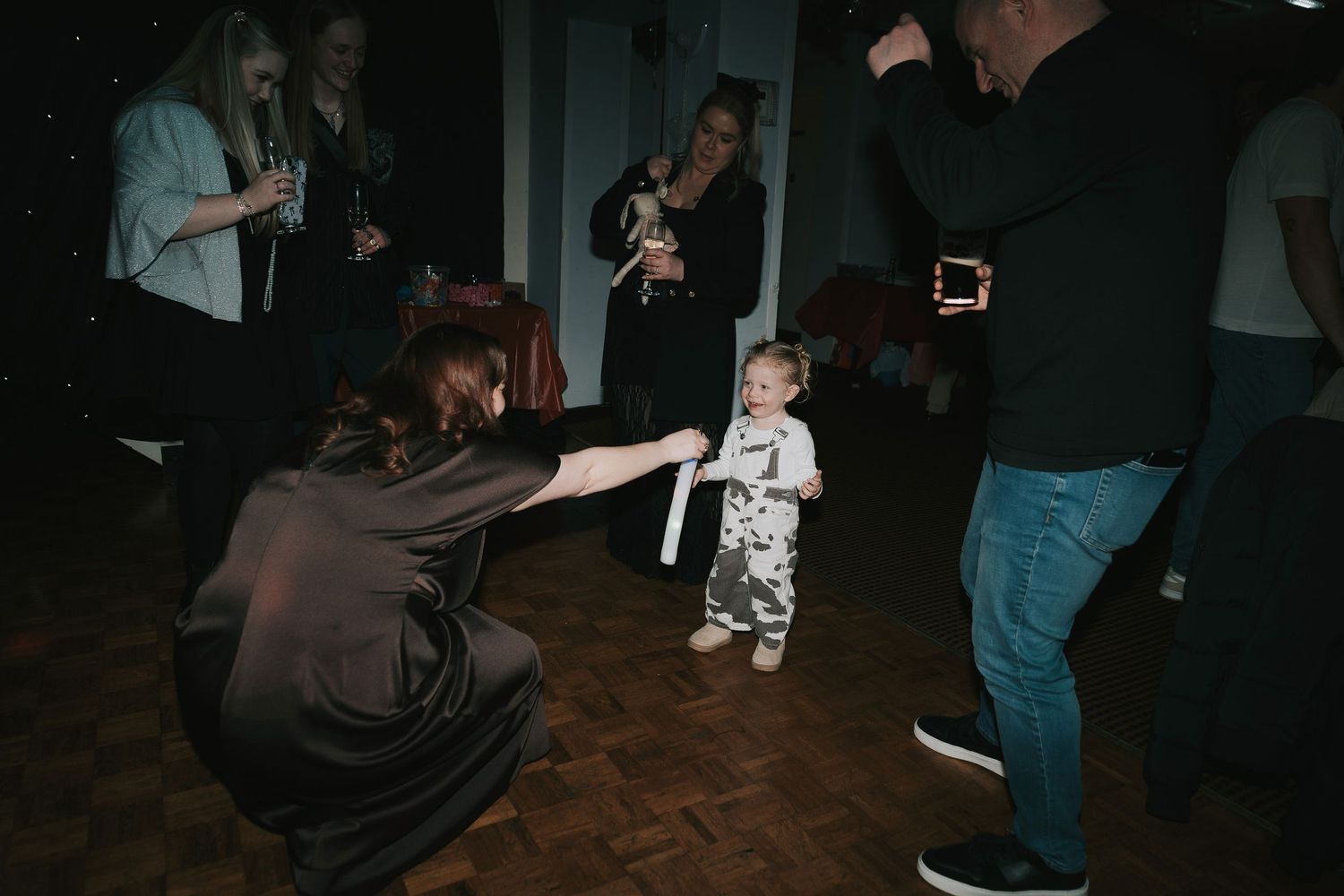 People dancing and moving on a dark dance floor during what appears to be a celebration or party.