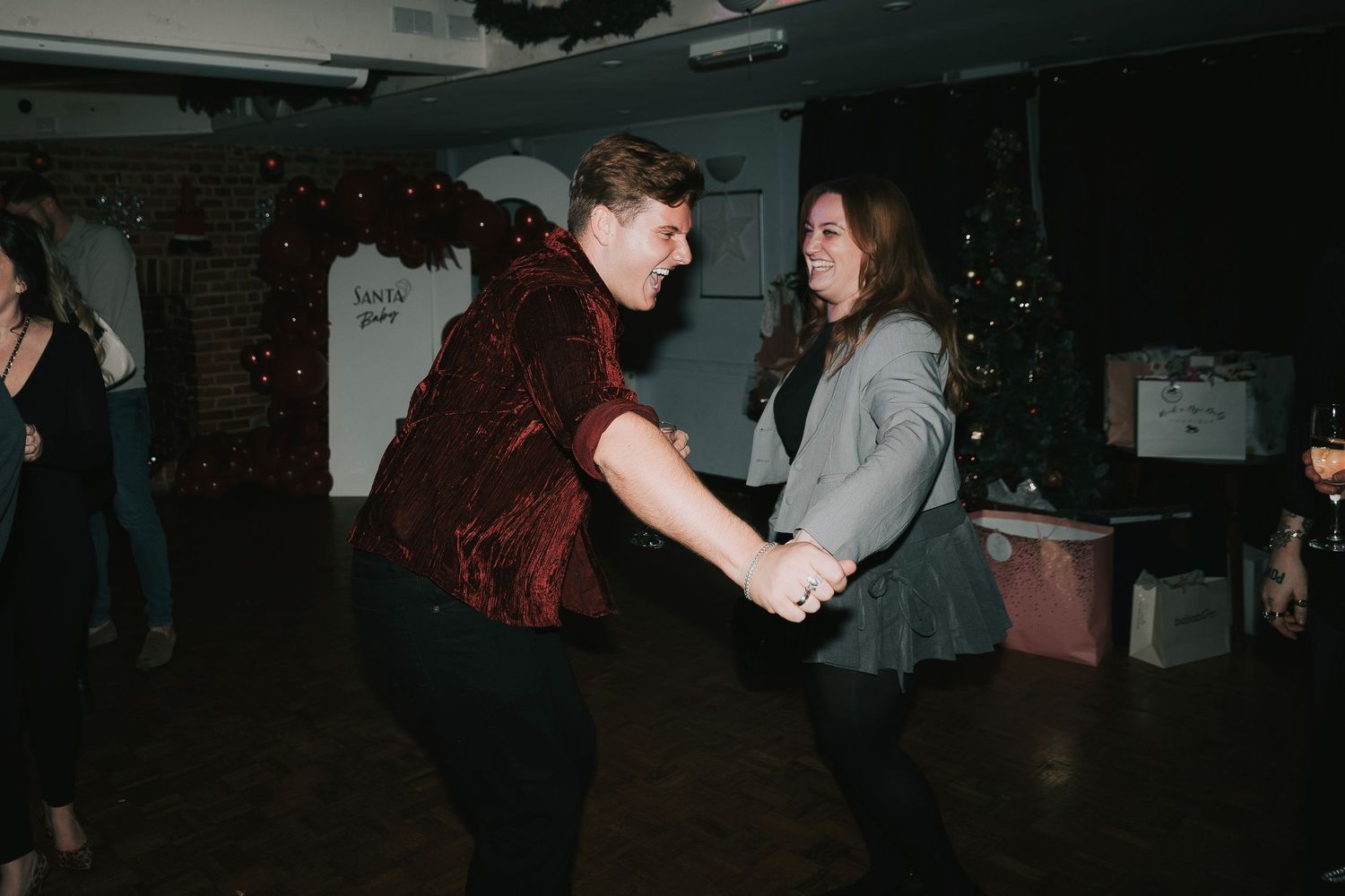 Party guests dancing and mingling in a dimly lit indoor venue space.