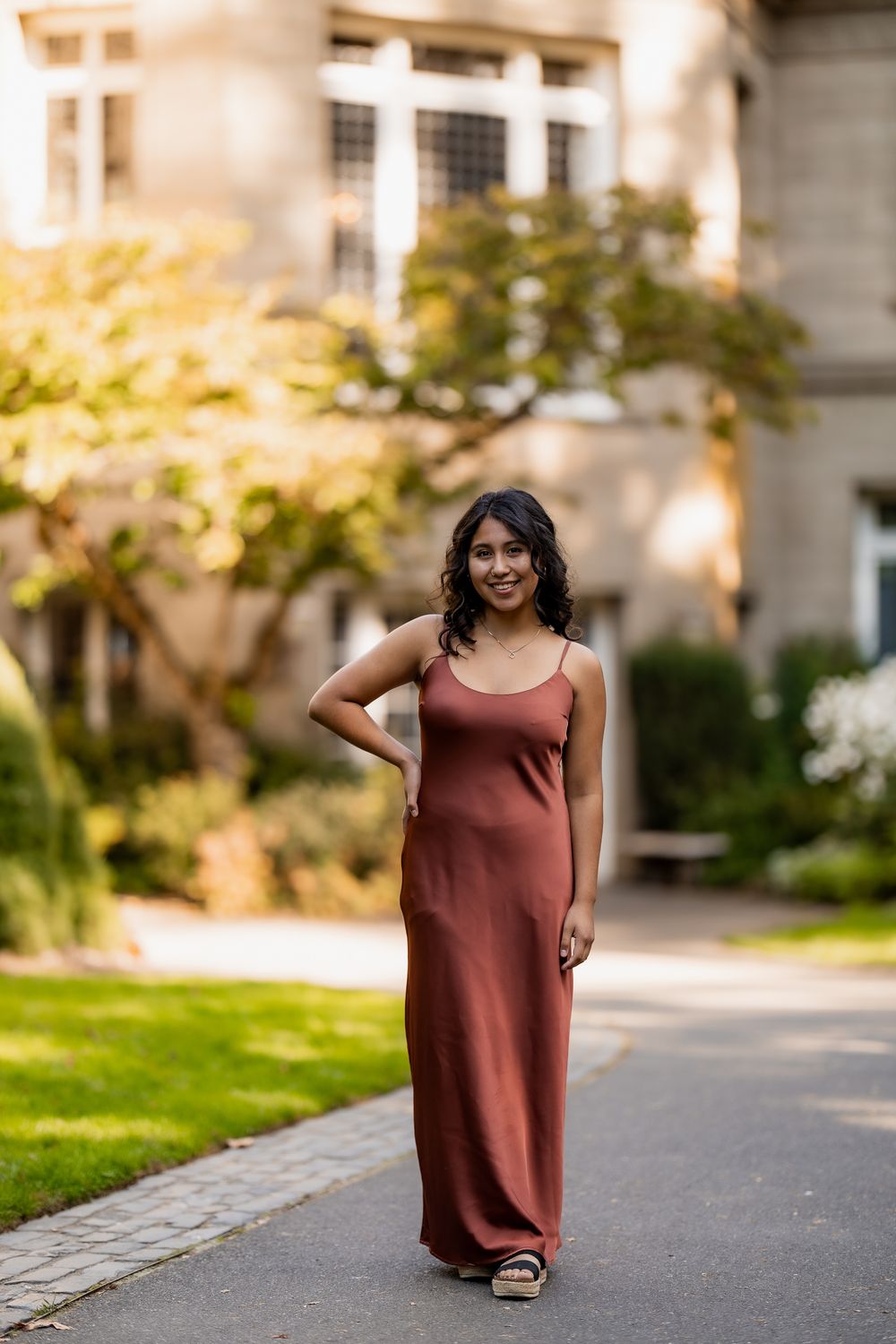 A series of photos showing someone walking in a brown dress on a paved path near buildings and grass.