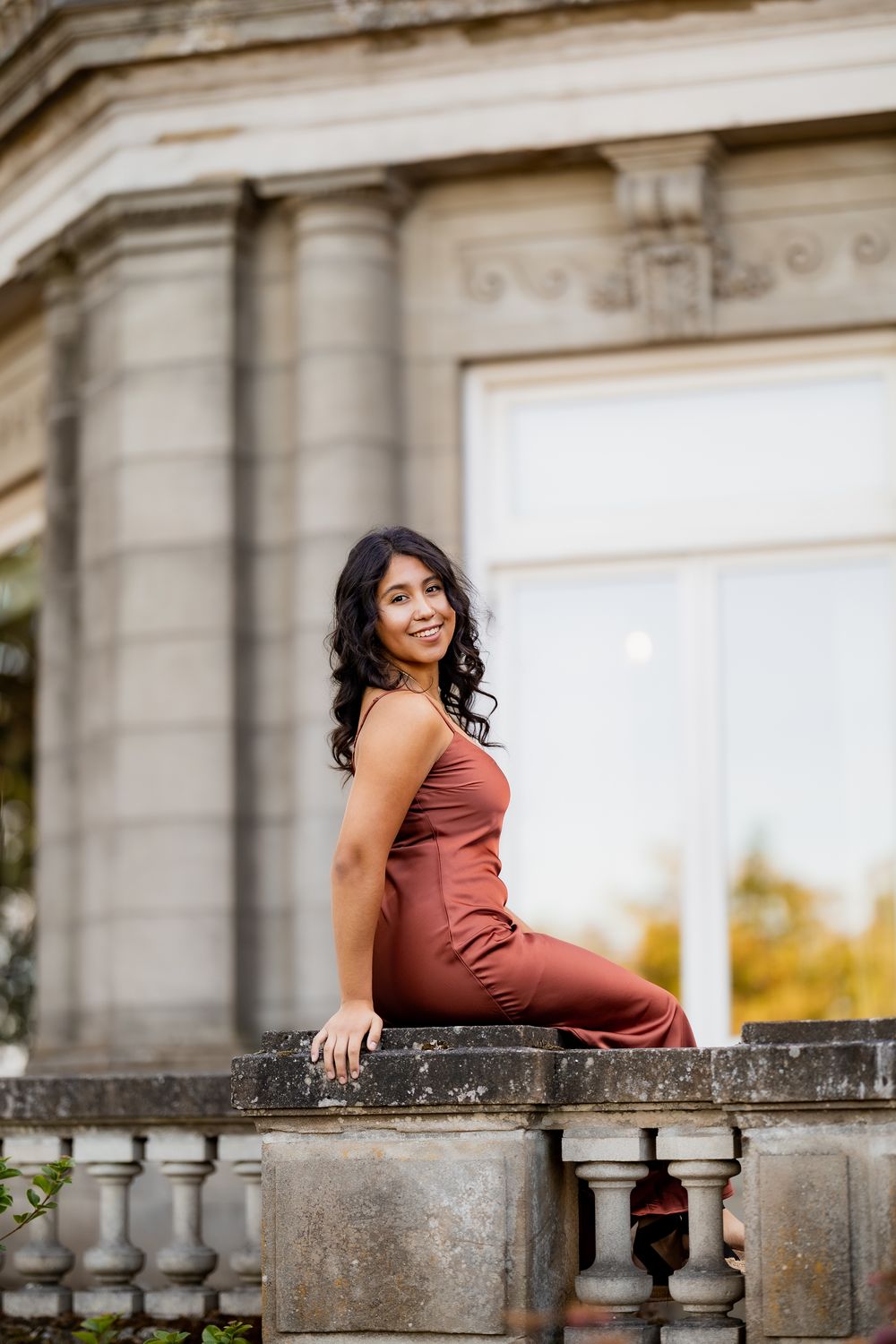 Outdoor portrait session at a classical stone balustrade during golden hour with architectural elements.