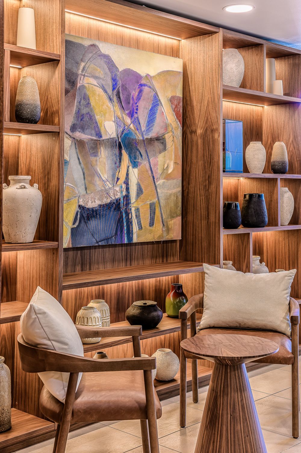 Modern interior design showroom with wood paneled walls featuring artwork, ceramic vases, and contemporary furniture.