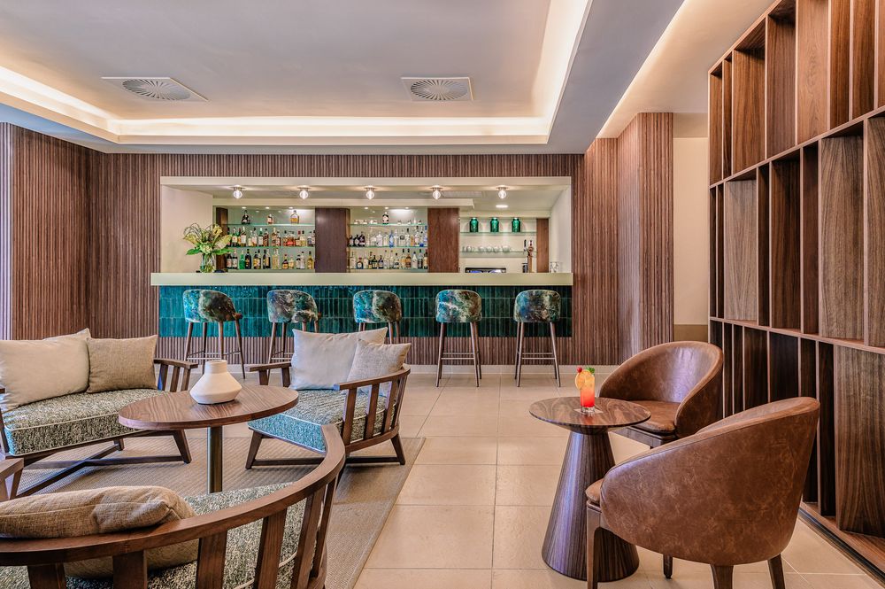Modern luxury hotel lobby with elegant wood paneling, recessed lighting, and comfortable brown leather seating areas.
