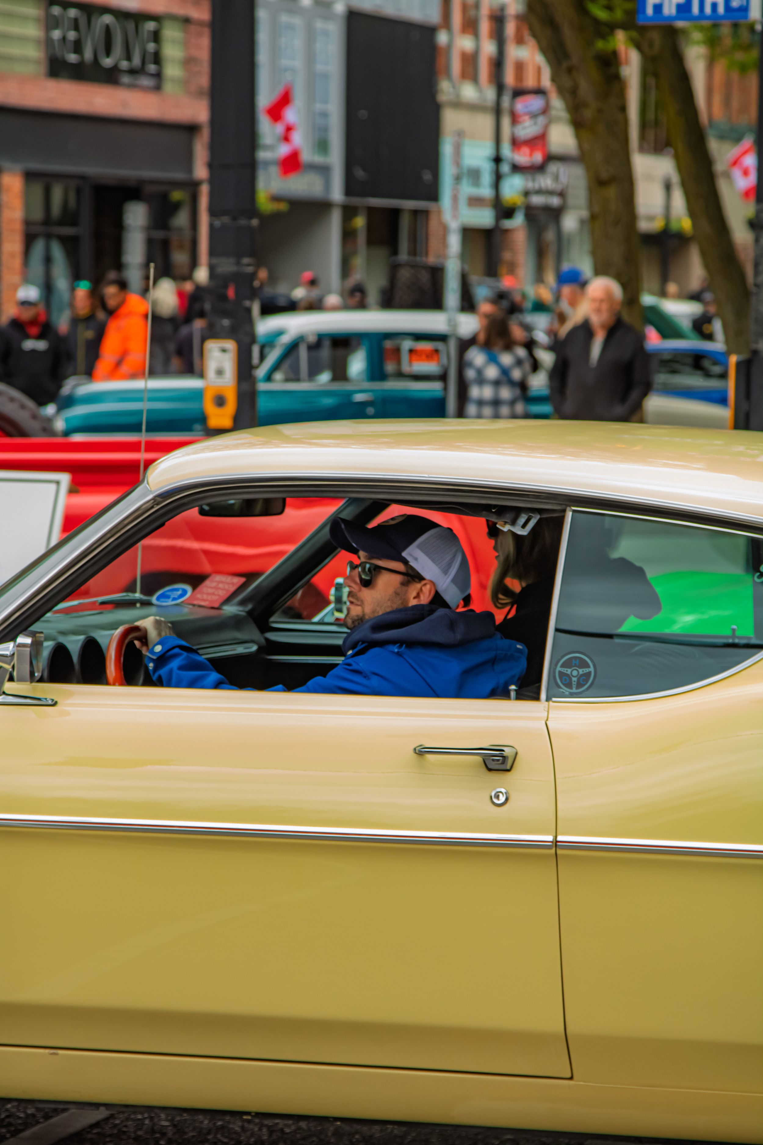 A classic yellow Plymouth muscle car with sleek lines and chrome trim parked at a car show.