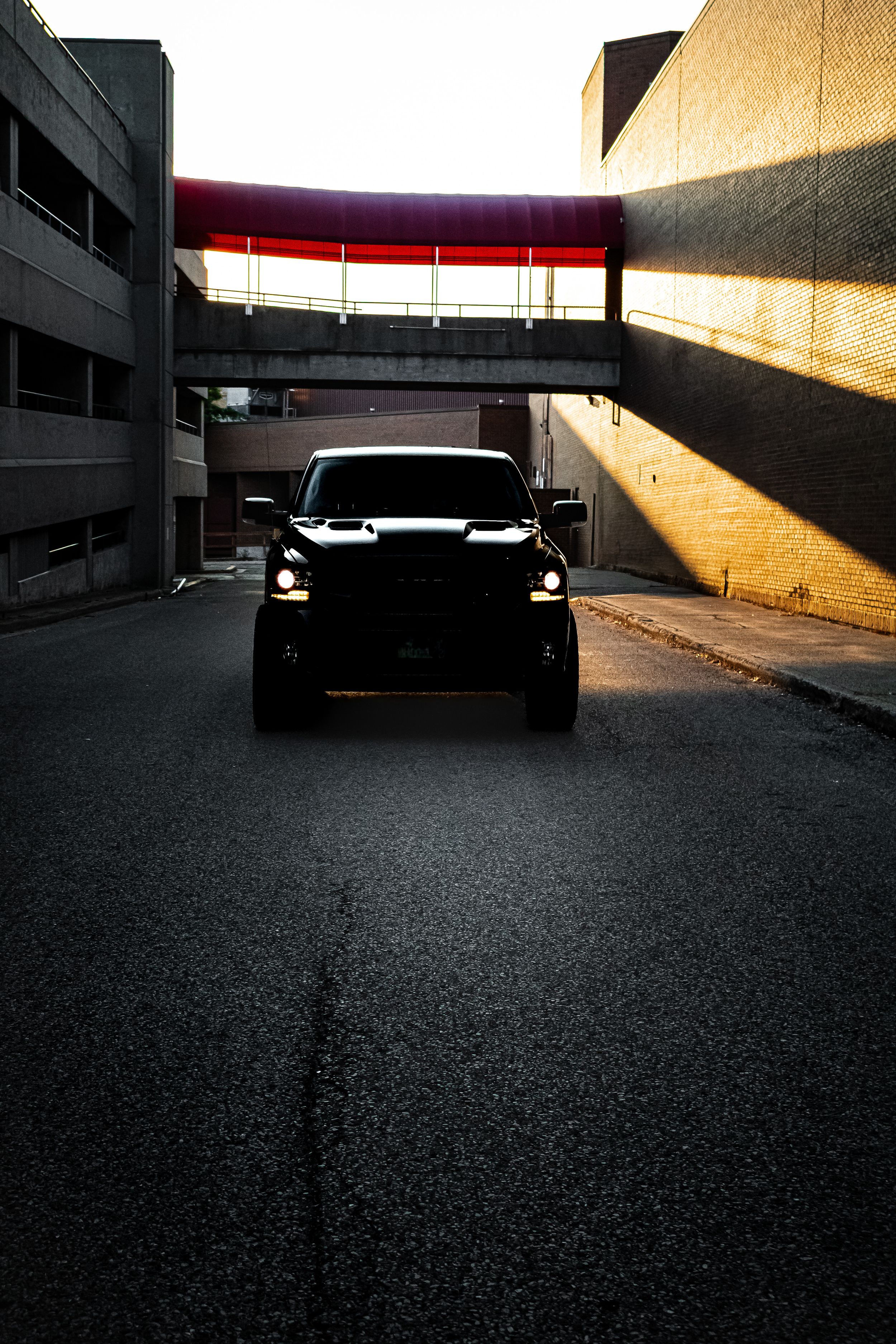 Silhouette of a car in a dimly lit parking garage with dramatic shadows and light beams streaming in.