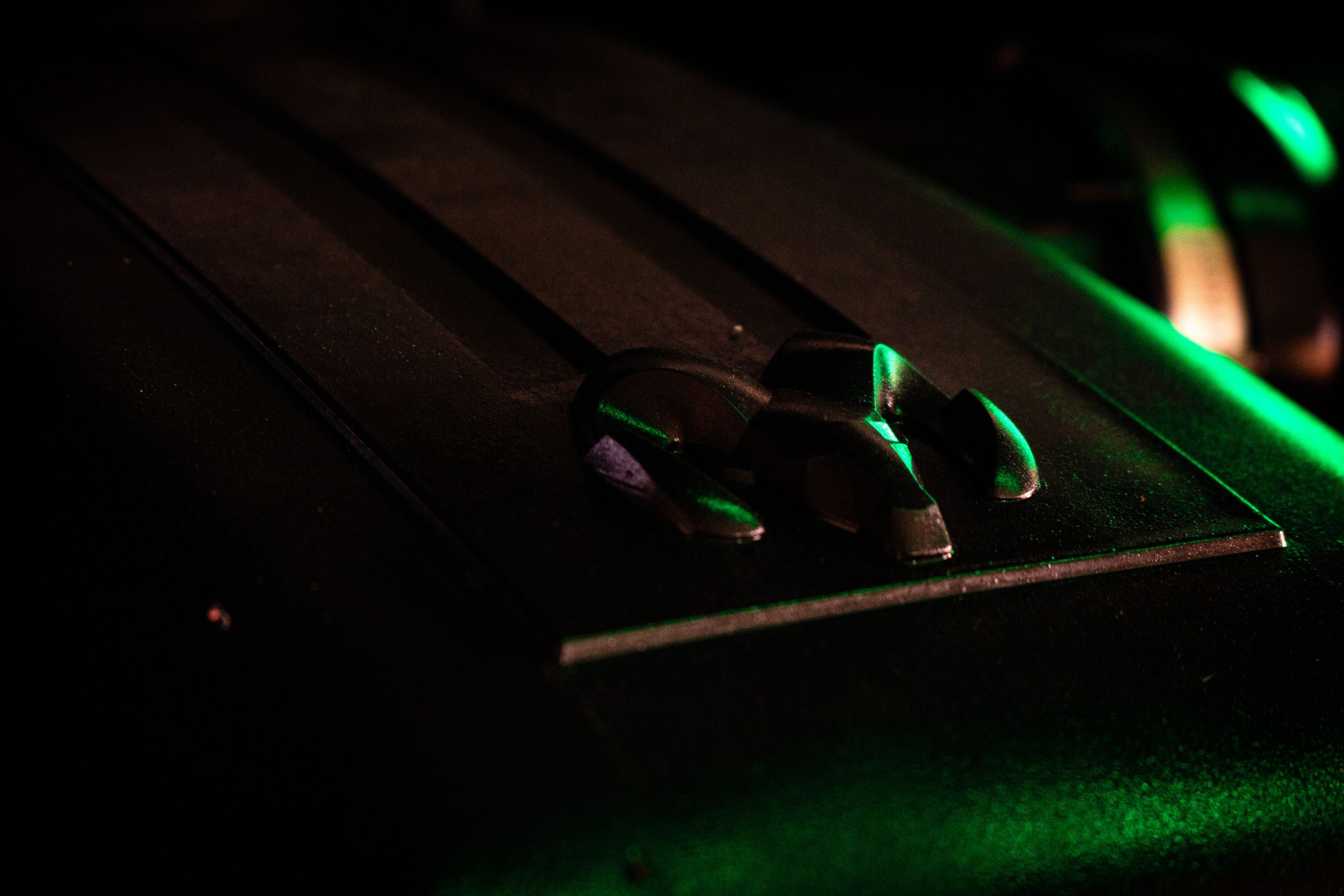 A turntable cartridge illuminated by green lights in a dark setting creates a moody atmospheric scene.