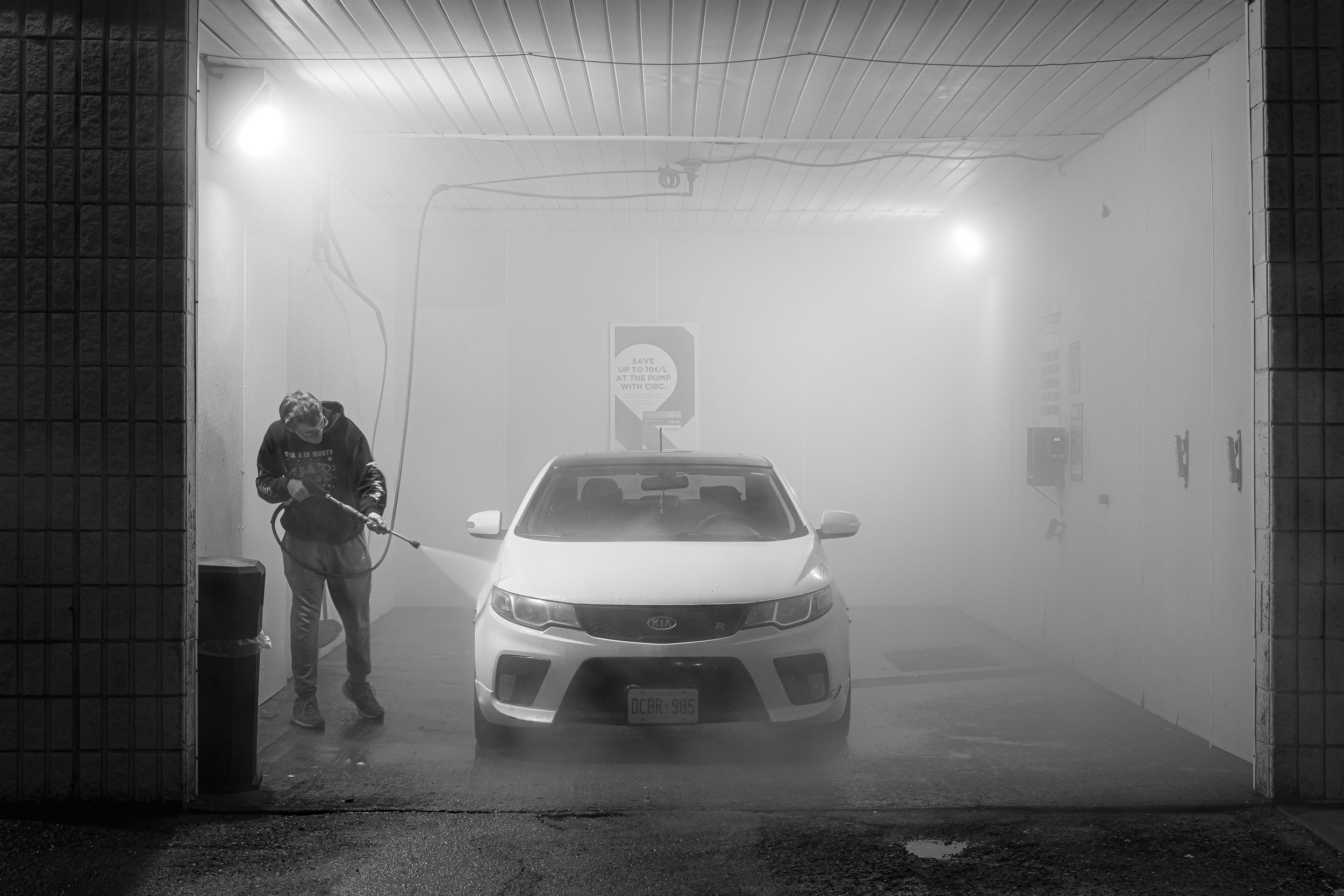 Foggy underground parking garage with silhouetted figures and cars visible through the atmospheric haze.