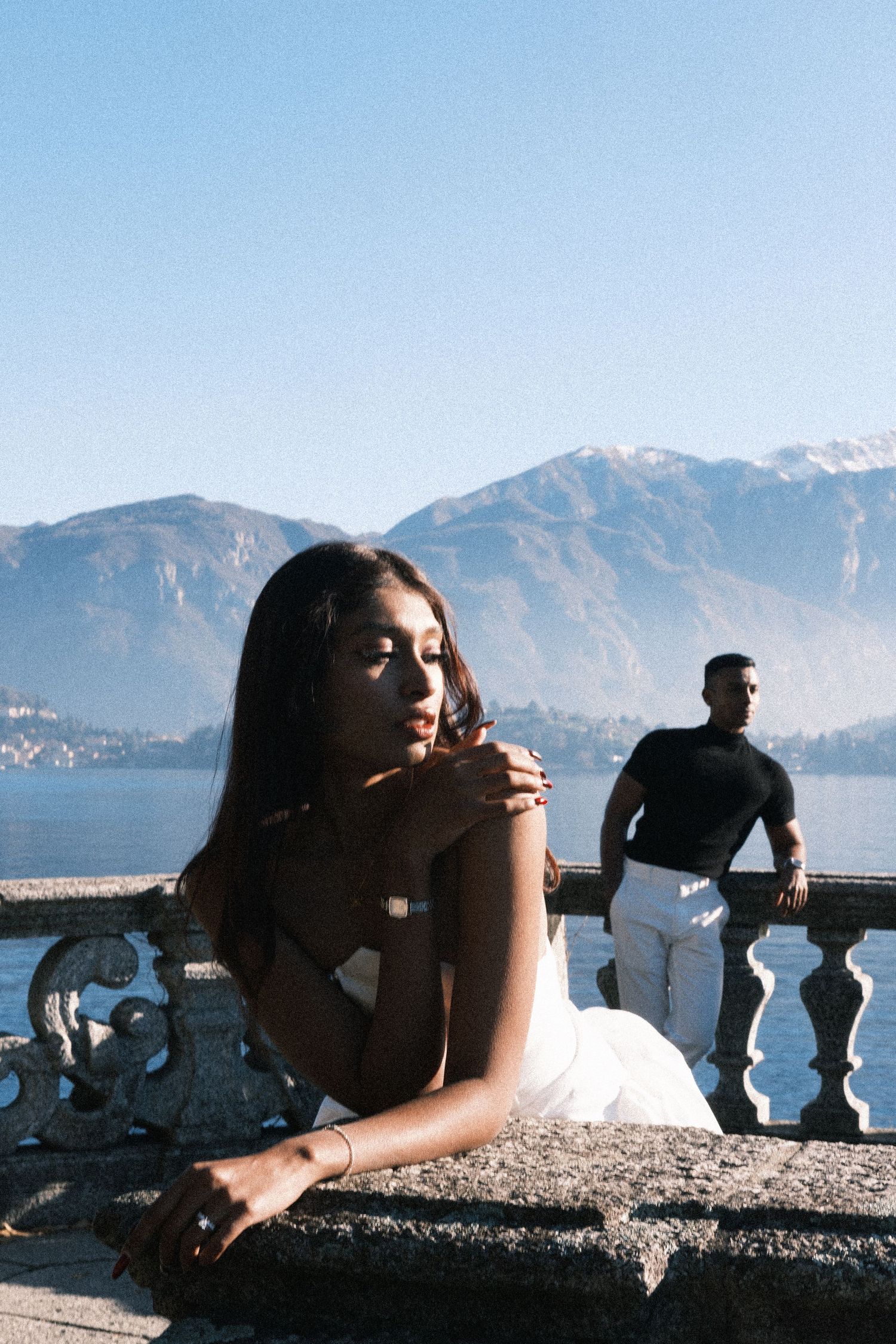 A series of film photographs showing people relaxing along a stone balcony overlooking a scenic mountain lake view.