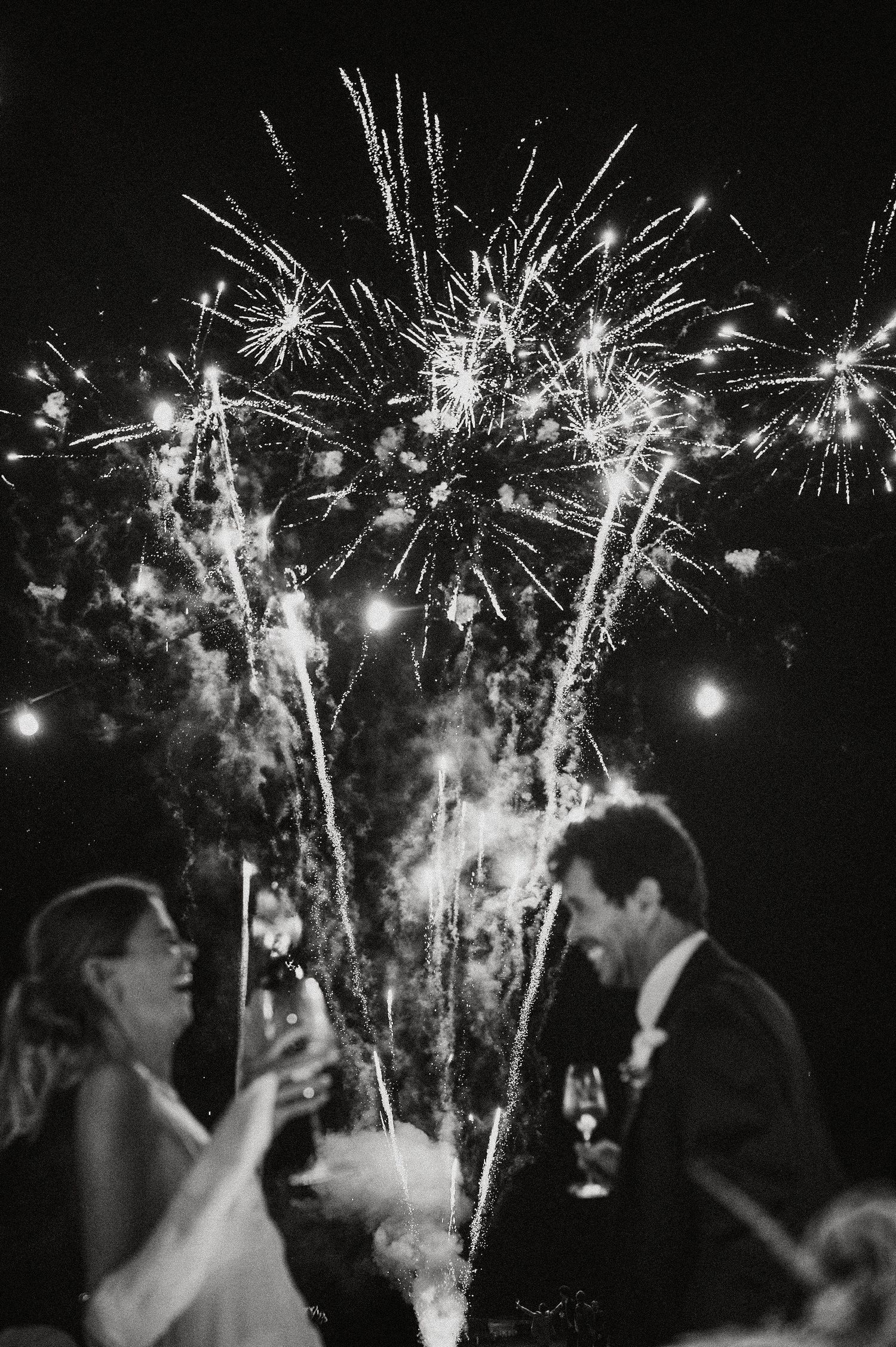 A series of black and white photos showing people celebrating with sparklers at a nighttime event.