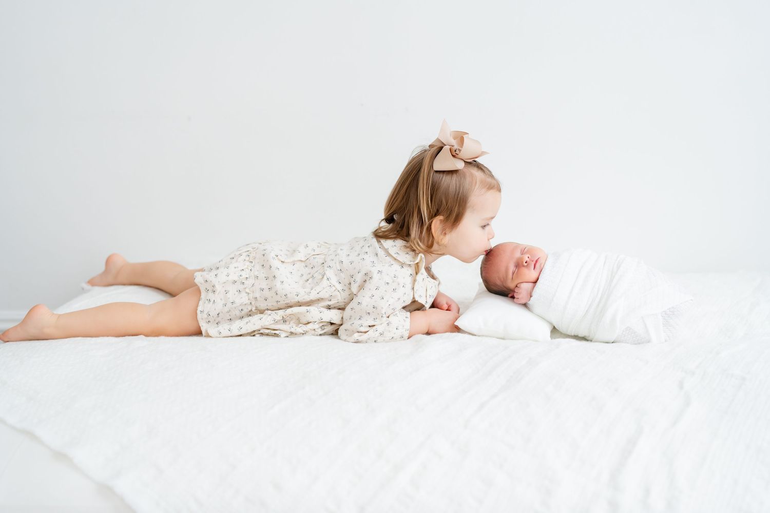 A person in white sleepwear lies comfortably on white bedding in a bright, minimalist setting.