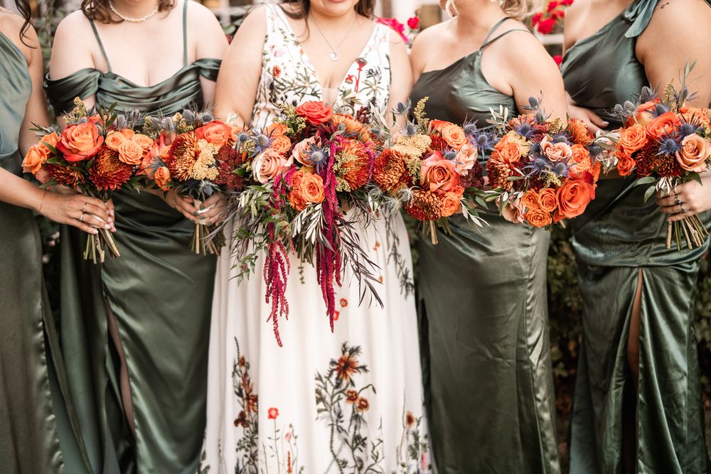 Colorful bridesmaids green dresses and orange flowers.