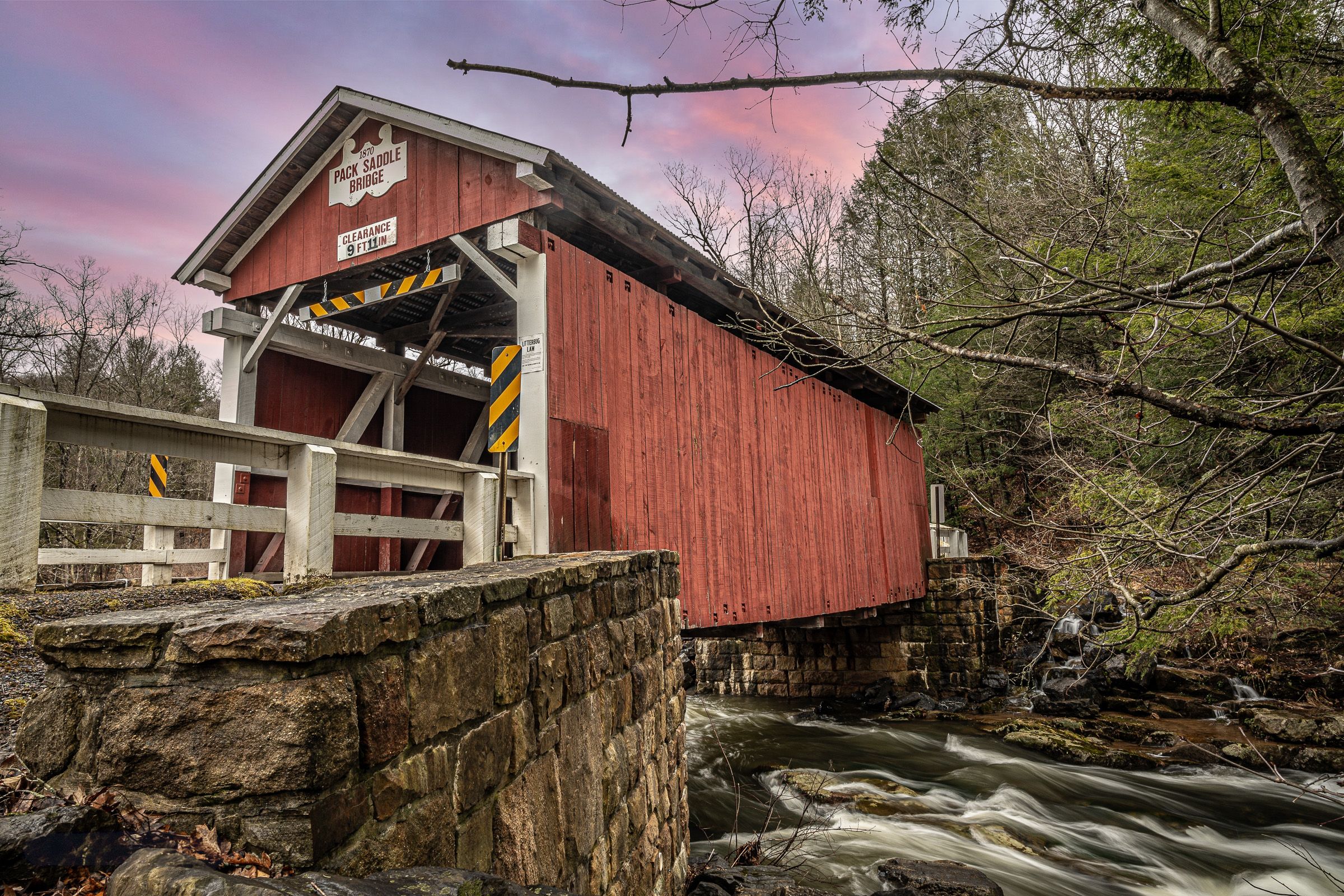 A scenic collection of red covered bridges over flowing streams in rural settings during sunset and autumn seasons.