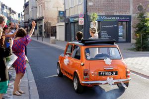 Series of playful photos with a vintage orange Mini Cooper car on a city street.