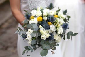 Wedding bouquet with white flowers, blue thistles and eucalyptus leaves.