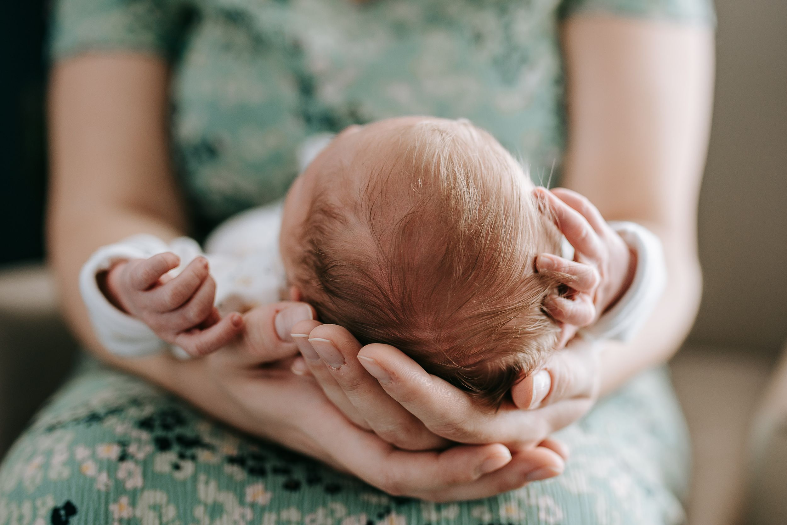 Close-up view of hands cradling sleeping newborn.