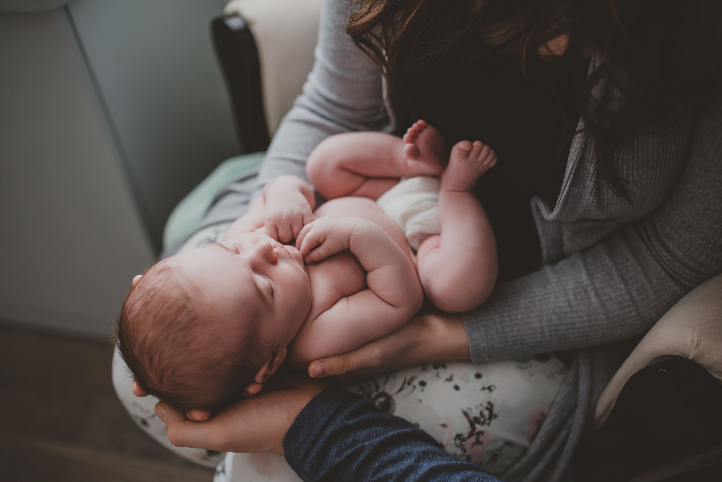 Close up view of infant feet and hands on gray fabric.