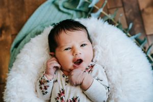 Peaceful newborn photography session on white fluffy blanket.