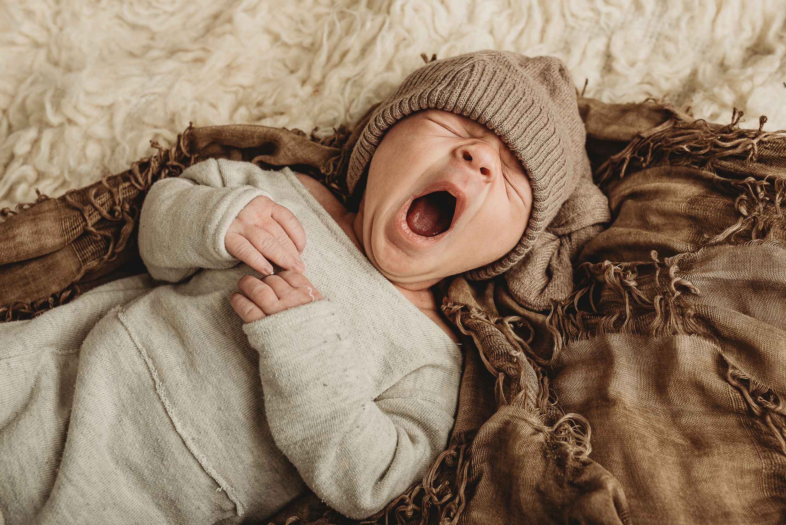 Baby lying on textured beige blanket with natural lighting.