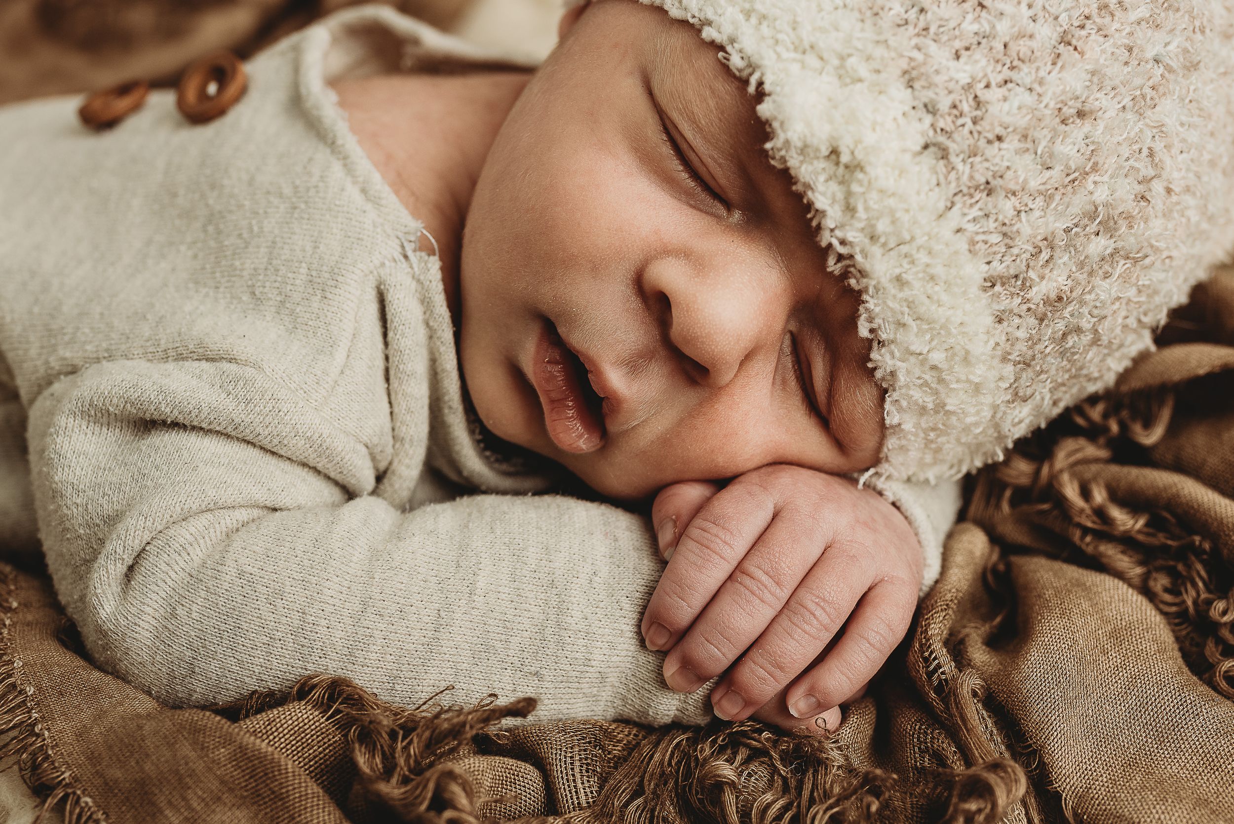 Peaceful sleeping baby in cream colored outfit on soft blanket.