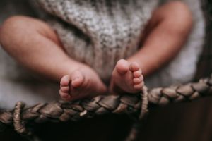 Close up of small bare feet resting on a textured knit blanket.