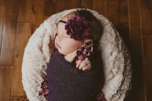 Overhead view of small child on cream colored plush rug with purple flowers.