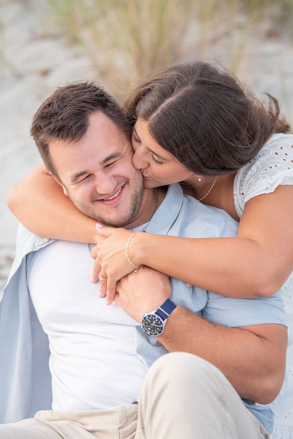 A tender moment between a couple as they embrace on a sandy beach.