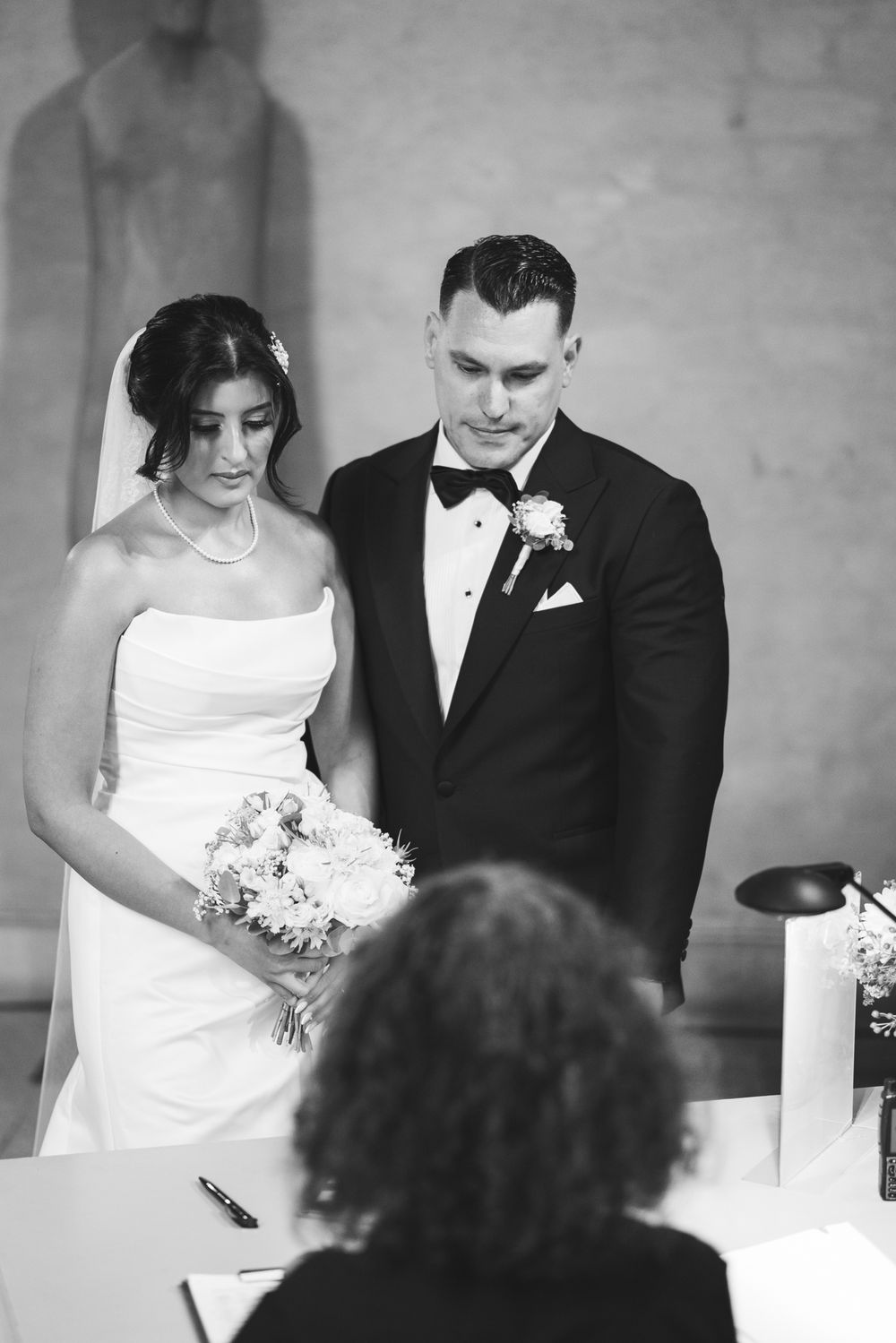 A series of black and white wedding ceremony photos showing a couple signing documents at their marriage registration.