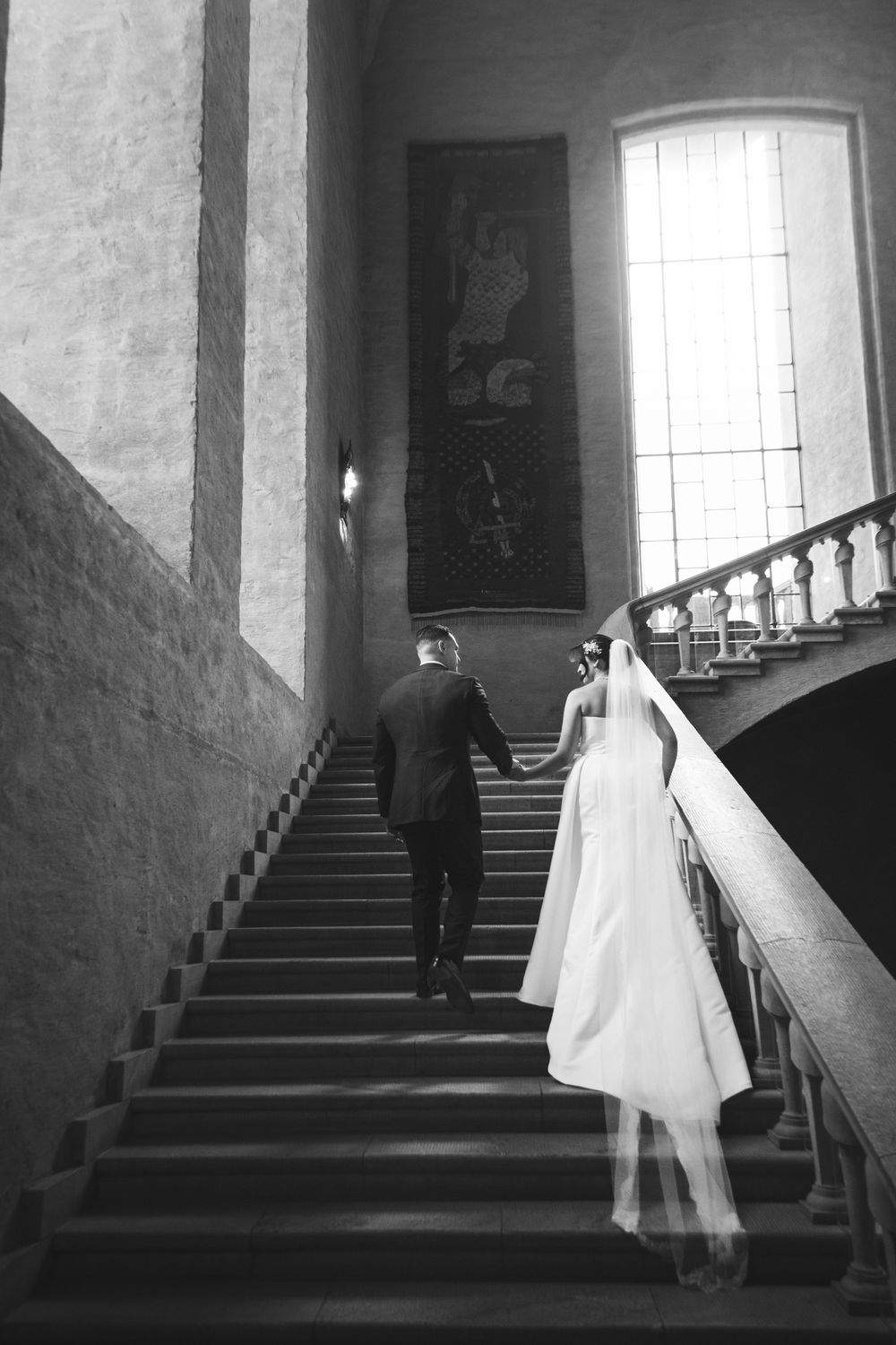 A black and white photo series showing a couple ascending a staircase in what appears to be a historic building.