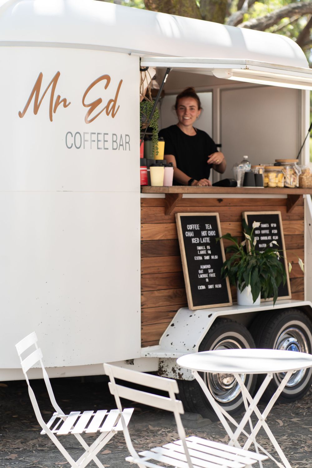 A white mobile coffee bar trailer called Mr Sol with outdoor seating setup.