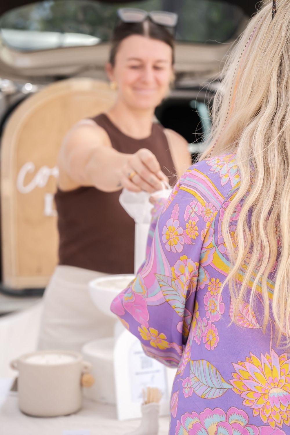 Two people enjoying coffee outdoors with colorful floral clothing visible.