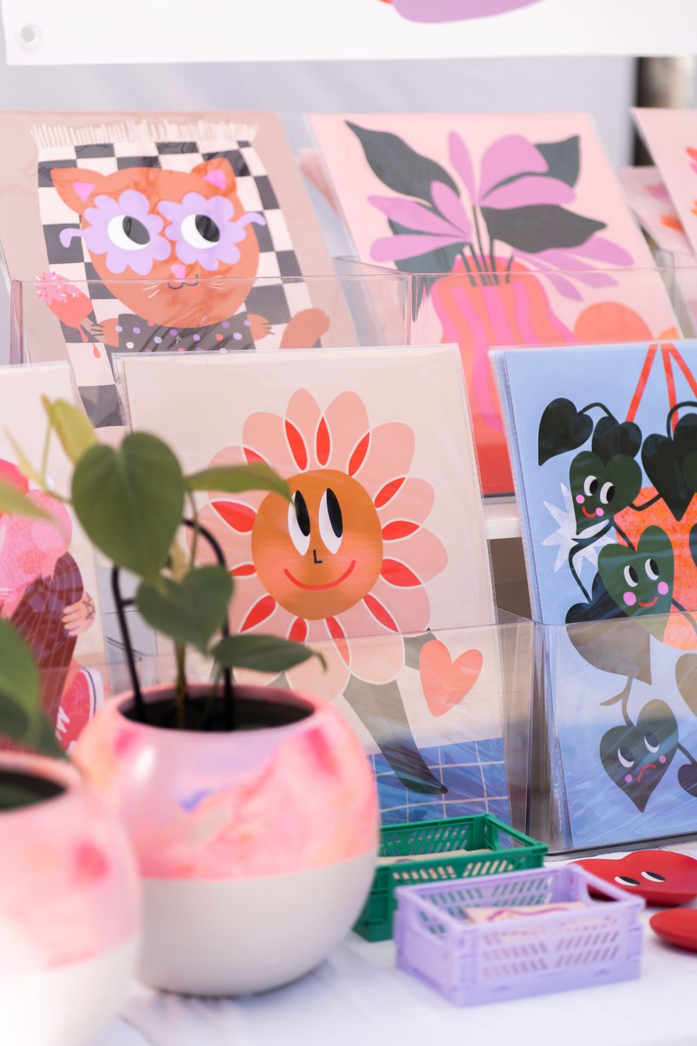 Cute illustrated greeting cards with floral patterns and cartoon characters displayed with a pink planter.