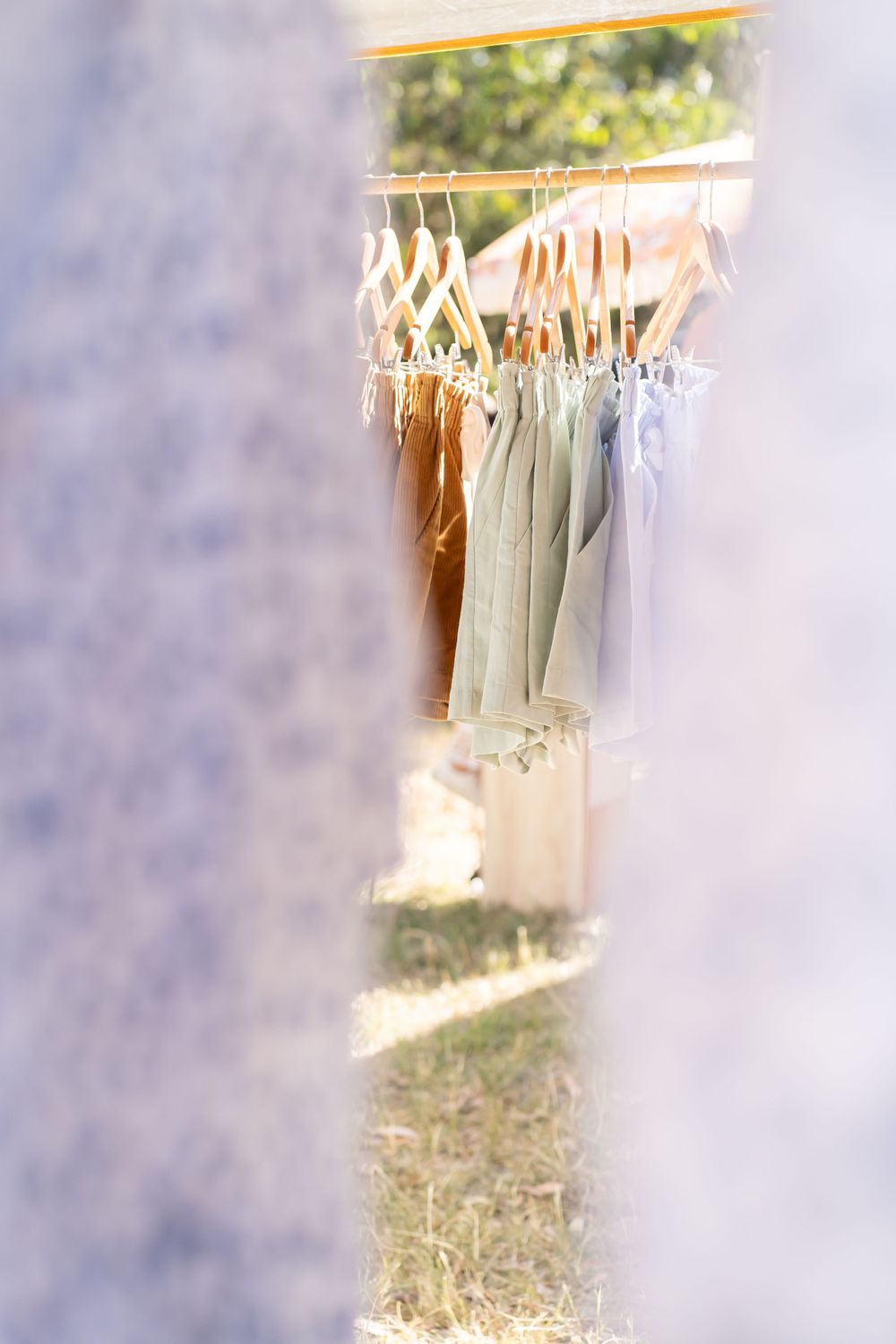 Soft focus pastel clothing items hanging on wooden hangers against blurred background.
