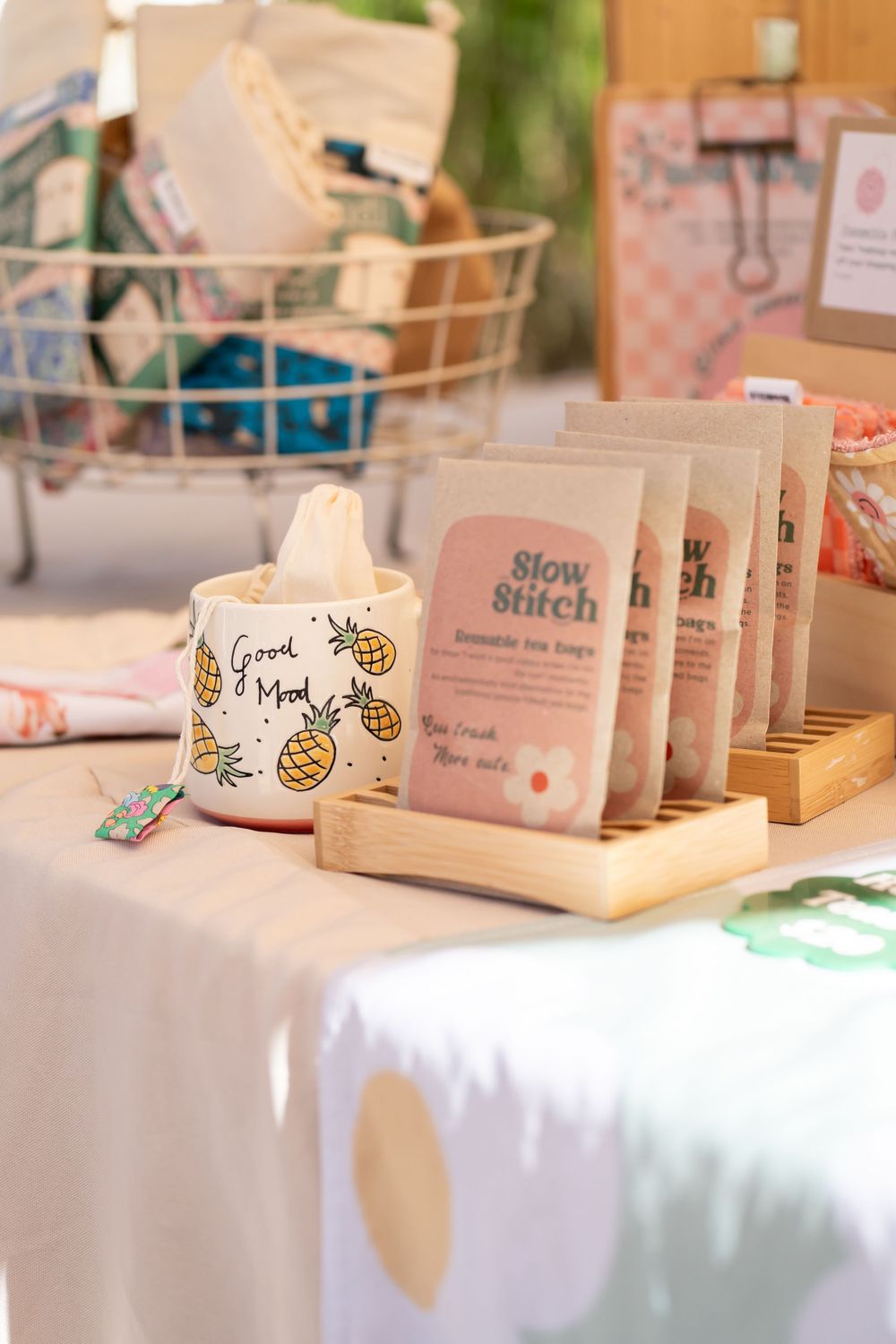 Retail display of Slow Stitch products and branded merchandise on white tablecloth.