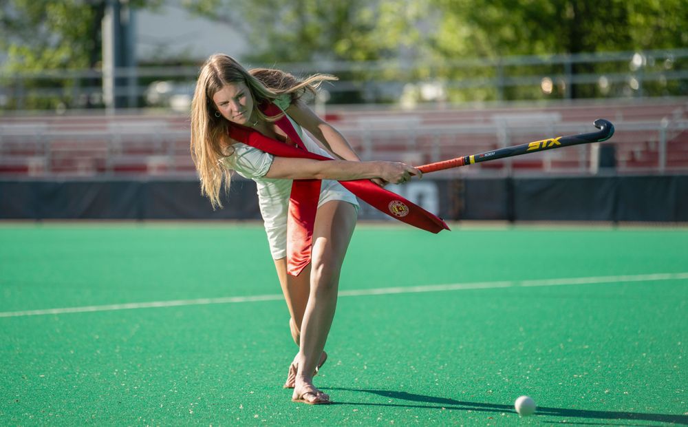 Field hockey player practicing stick skills on green turf field during training session.