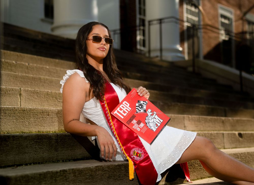 Athletic team member in red and white uniform poses on stadium steps.