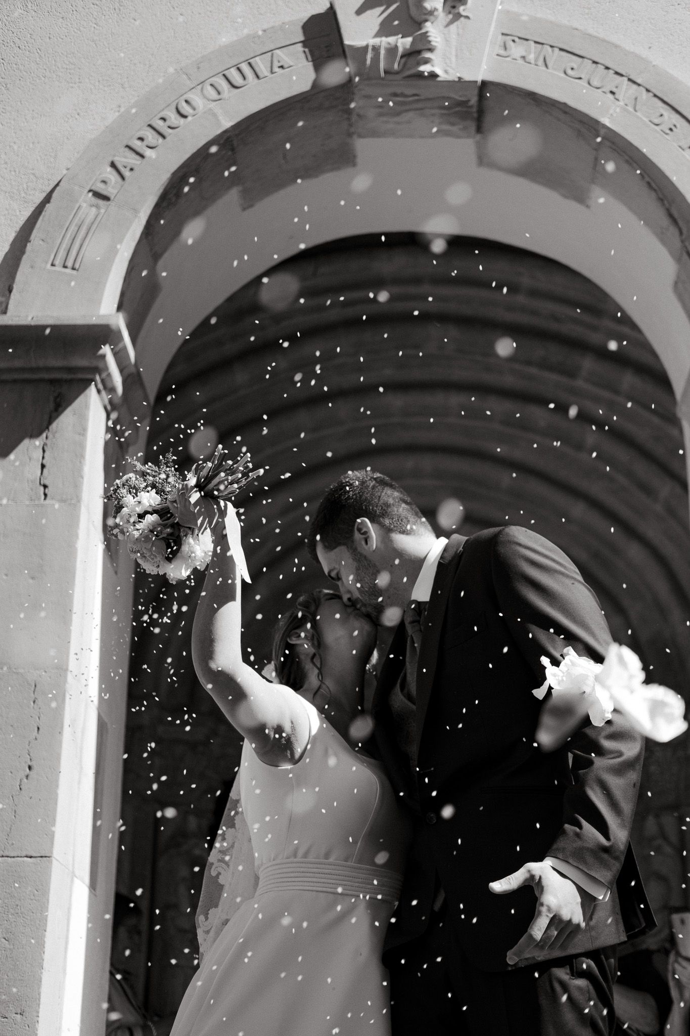 Celebratory moment with confetti and joy under a stone archway in black and white.