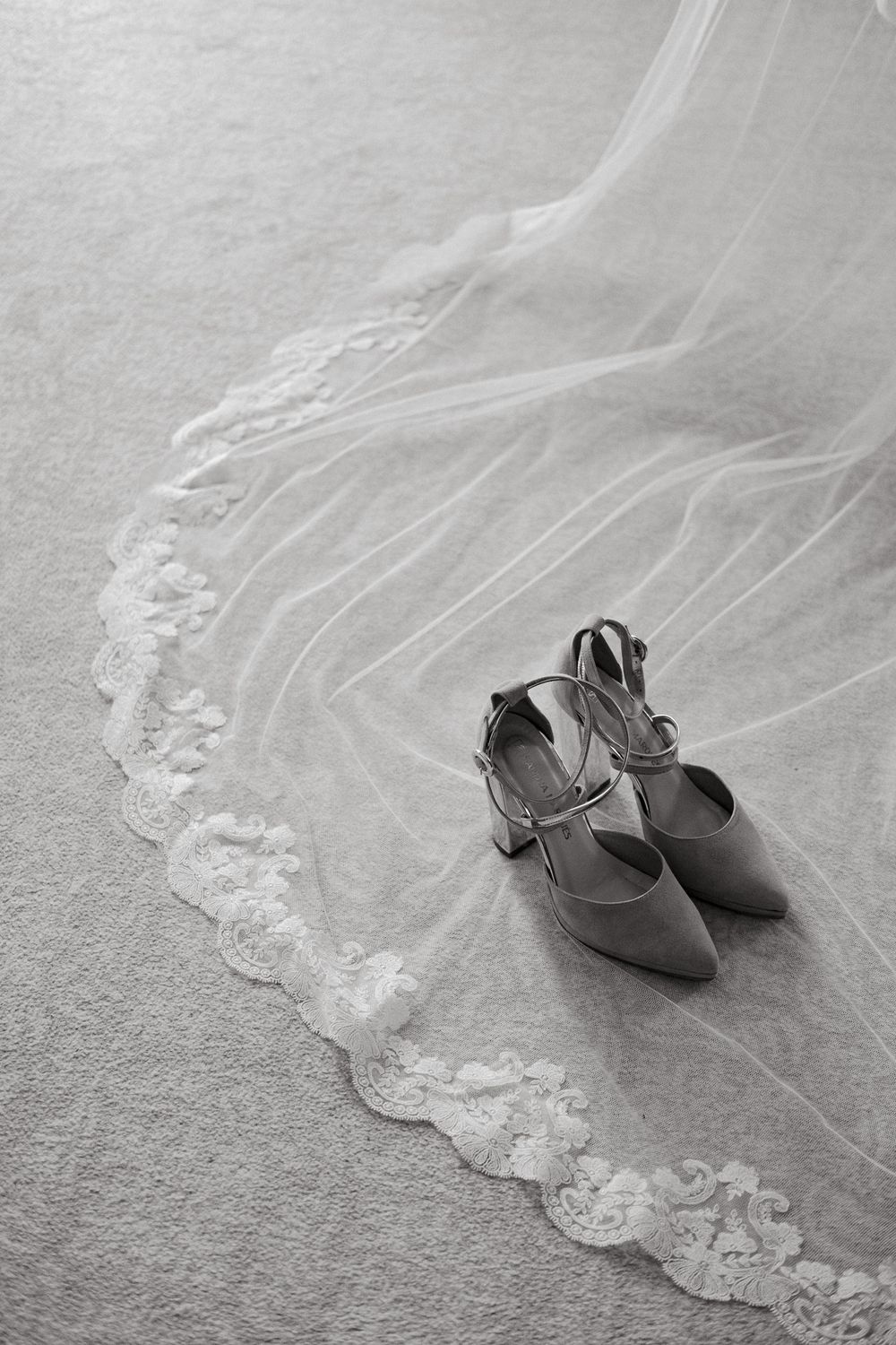 Elegant bridal shoes placed beside lace trim of a wedding dress.