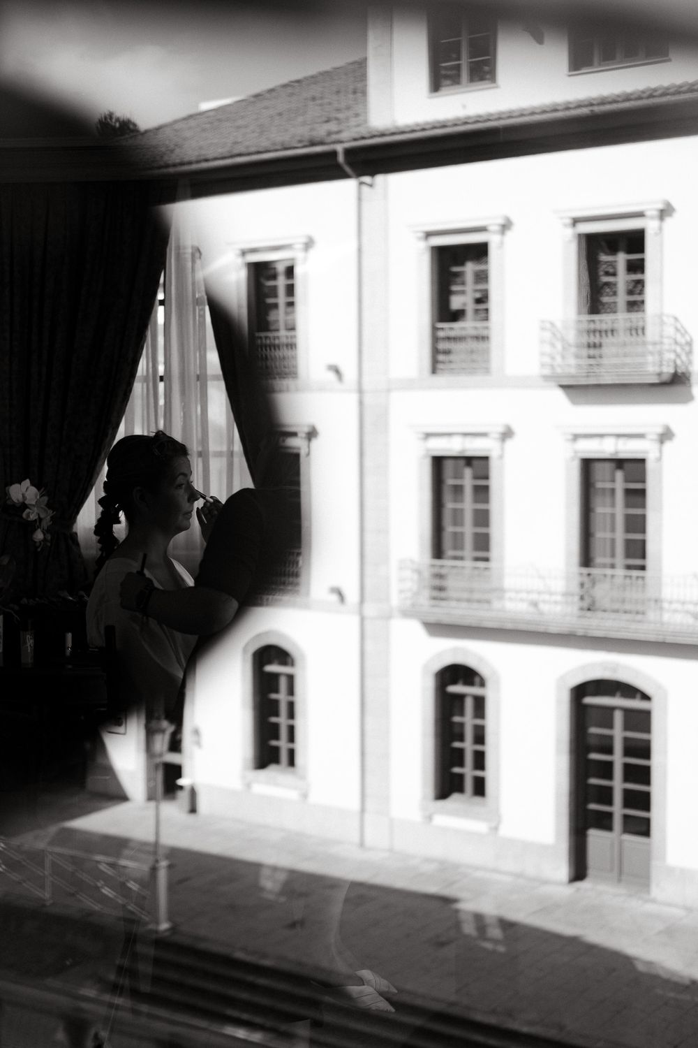 Black and white view of an elegant building exterior through window.
