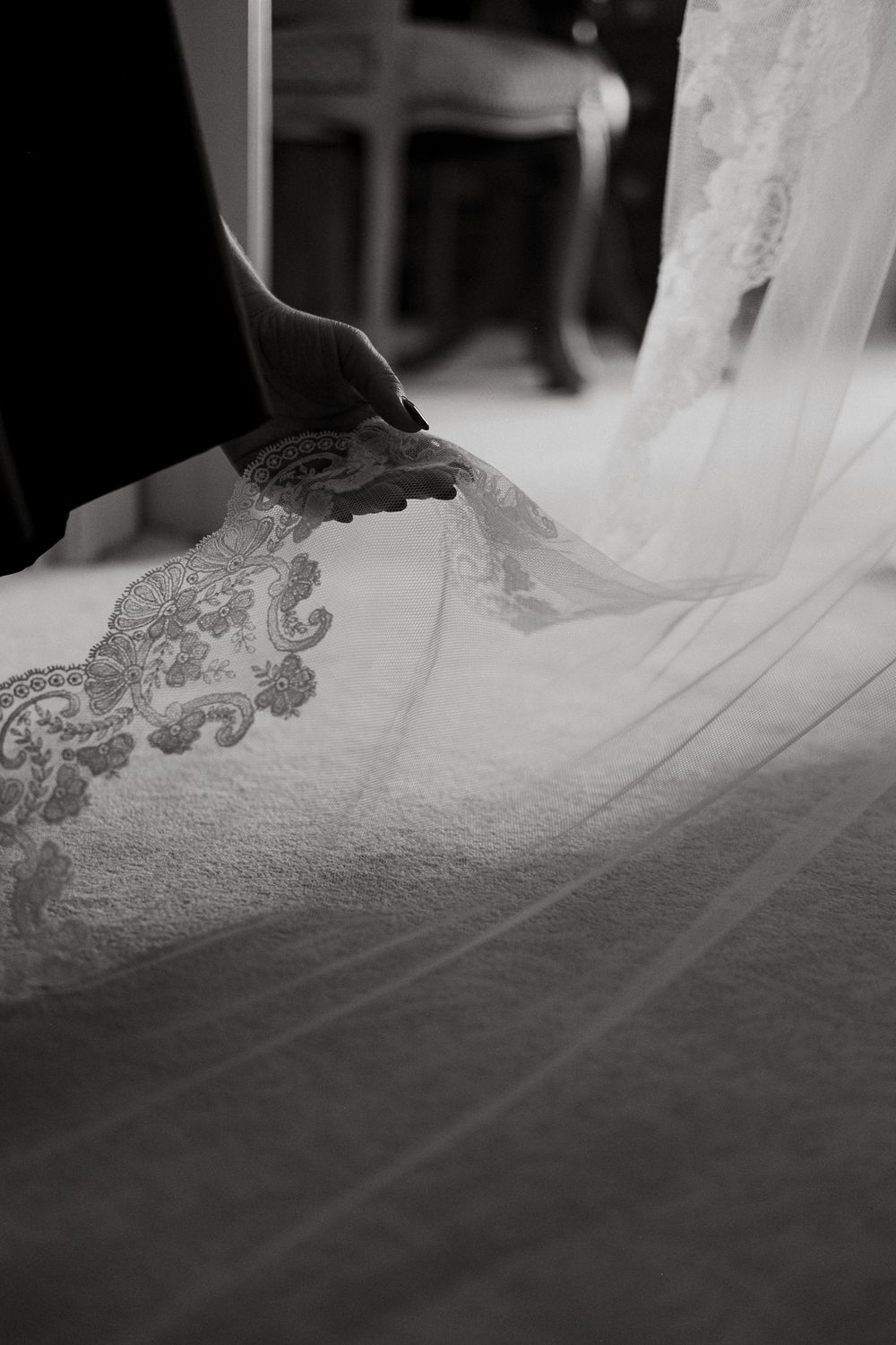 Detailed shot of hands arranging wedding dress lace.