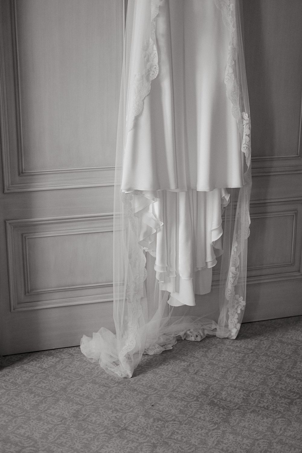 Wedding dress hanging elegantly against a paneled wall.