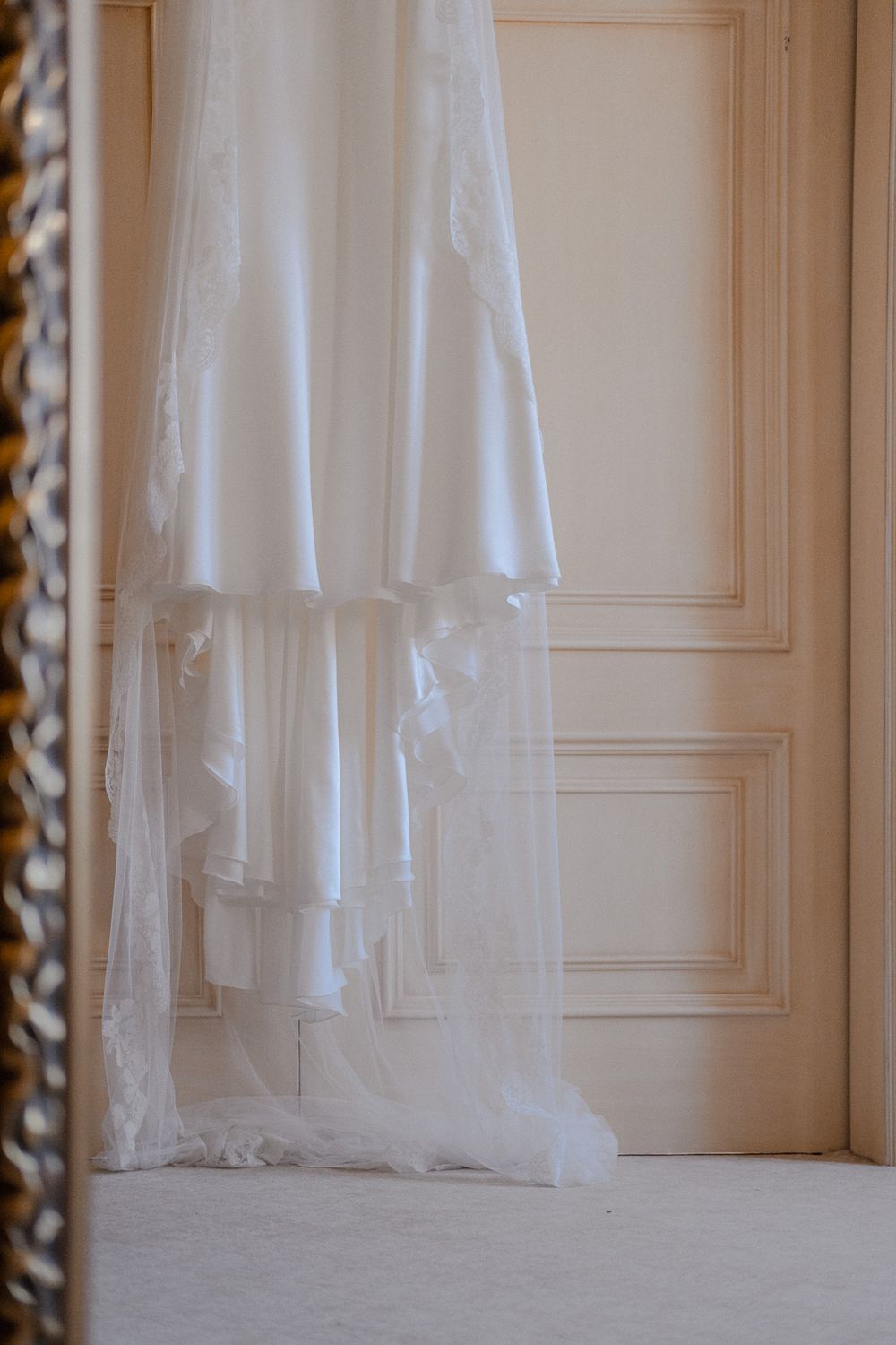 A flowing white wedding dress veil draped against a classic paneled door.