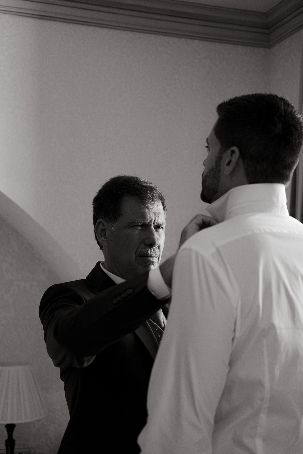 Two people in formal attire having a conversation in a dimly lit room.