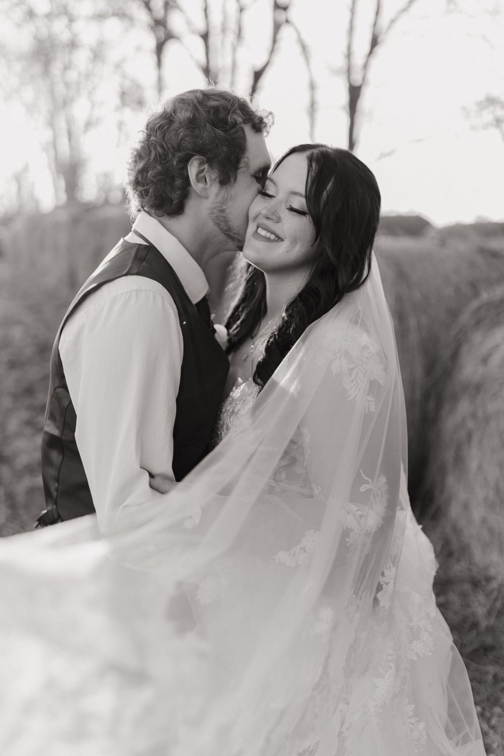 Romantic black and white wedding portrait capturing intimate moment in natural setting.